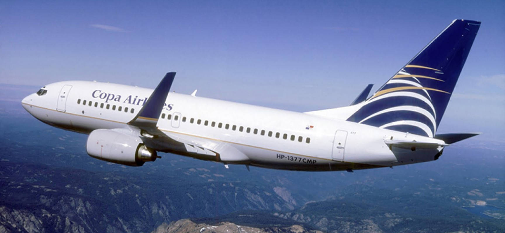 飛機 桌布 壁紙 — 一架巴拿馬航空客機在晴朗藍天下翱翔於山區地形之上。