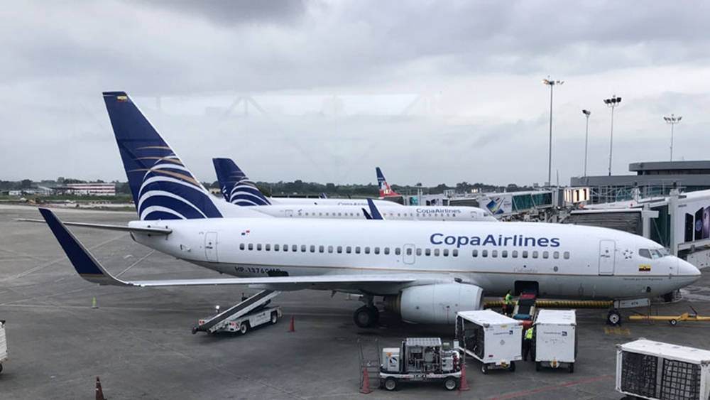 Airport 桌布 壁紙 — 一架巴拿馬航空飛機停泊在機場閘口，地勤人員和設備在陰天之下。