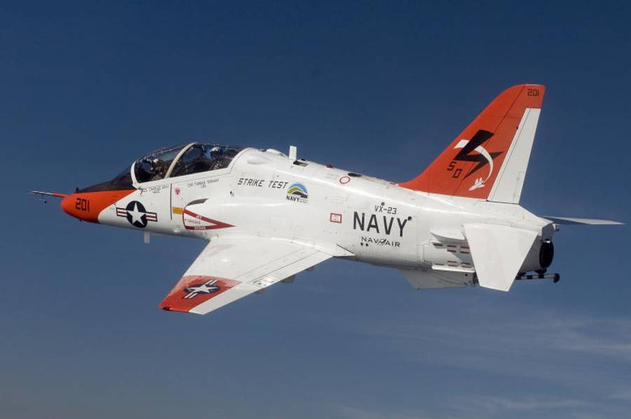 u s navy 桌布 壁紙 — 一架帶有「STRIKE TEST」標記的白色和橙色海軍噴射機在清澈的藍天中翱翔。