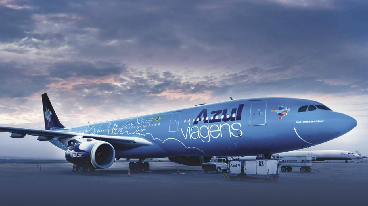 飛機 桌布 壁紙 — 一架帶有「viagens」品牌標誌的藍色Azul Airlines飛機停在機場停機坪上，天空多雲，正值黃昏。