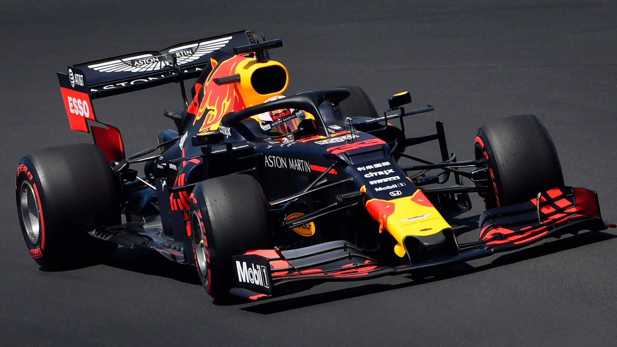 紅牛 桌布 壁紙 — 一架帶有Aston Martin品牌標誌的Red Bull Racing一級方程式賽車在陽光照耀的賽道上飛馳。