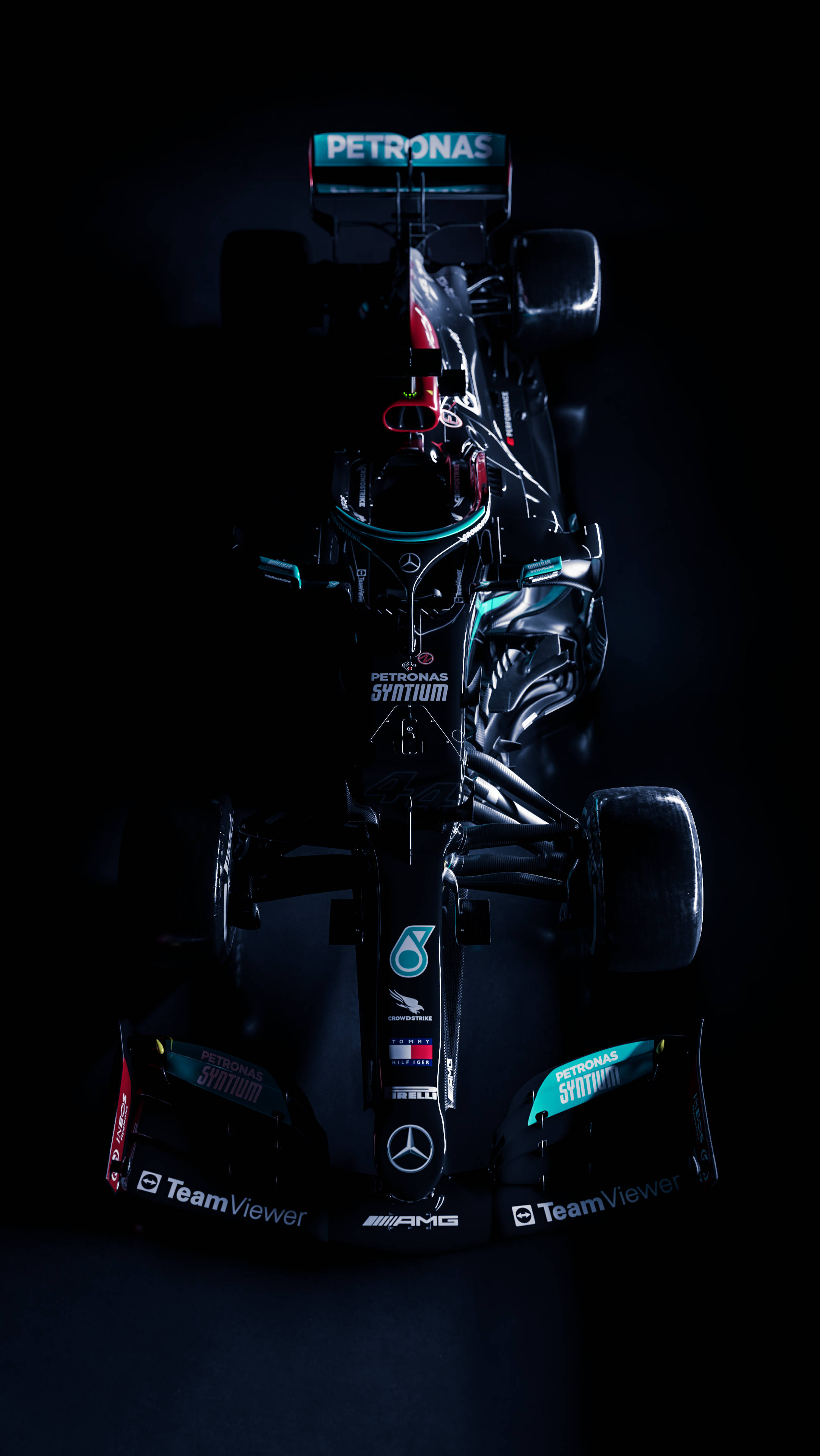Mercedes 桌布 壁紙 — 一架帶有Petronas品牌標誌的時尚黑色和藍綠色一級方程式賽車，在漆黑背景上從上方戲劇性地打光。