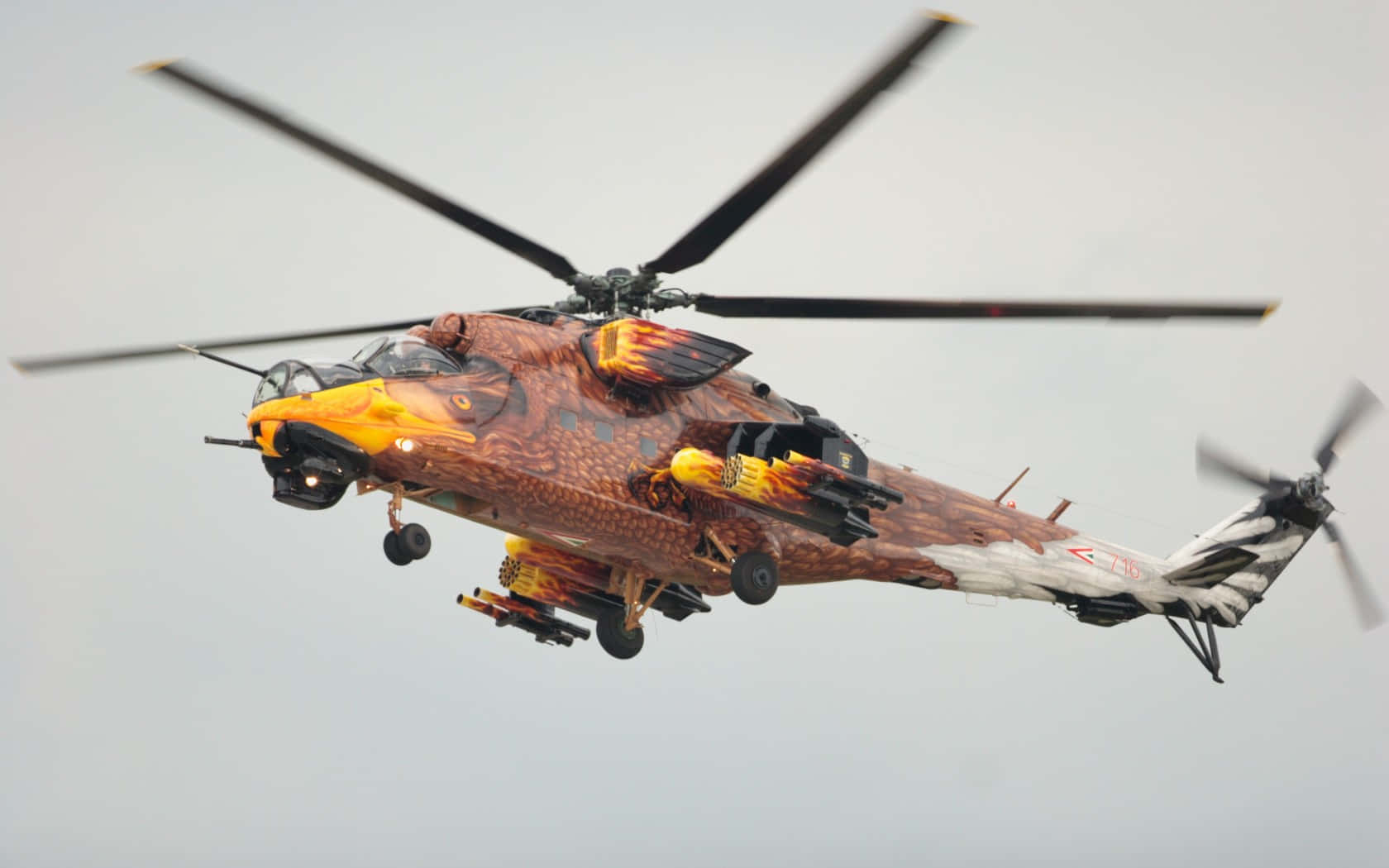Helicopters 桌布 壁紙 — 一架帶有火焰龍皮塗裝的軍用直升機在蒼白的天空中飛行。