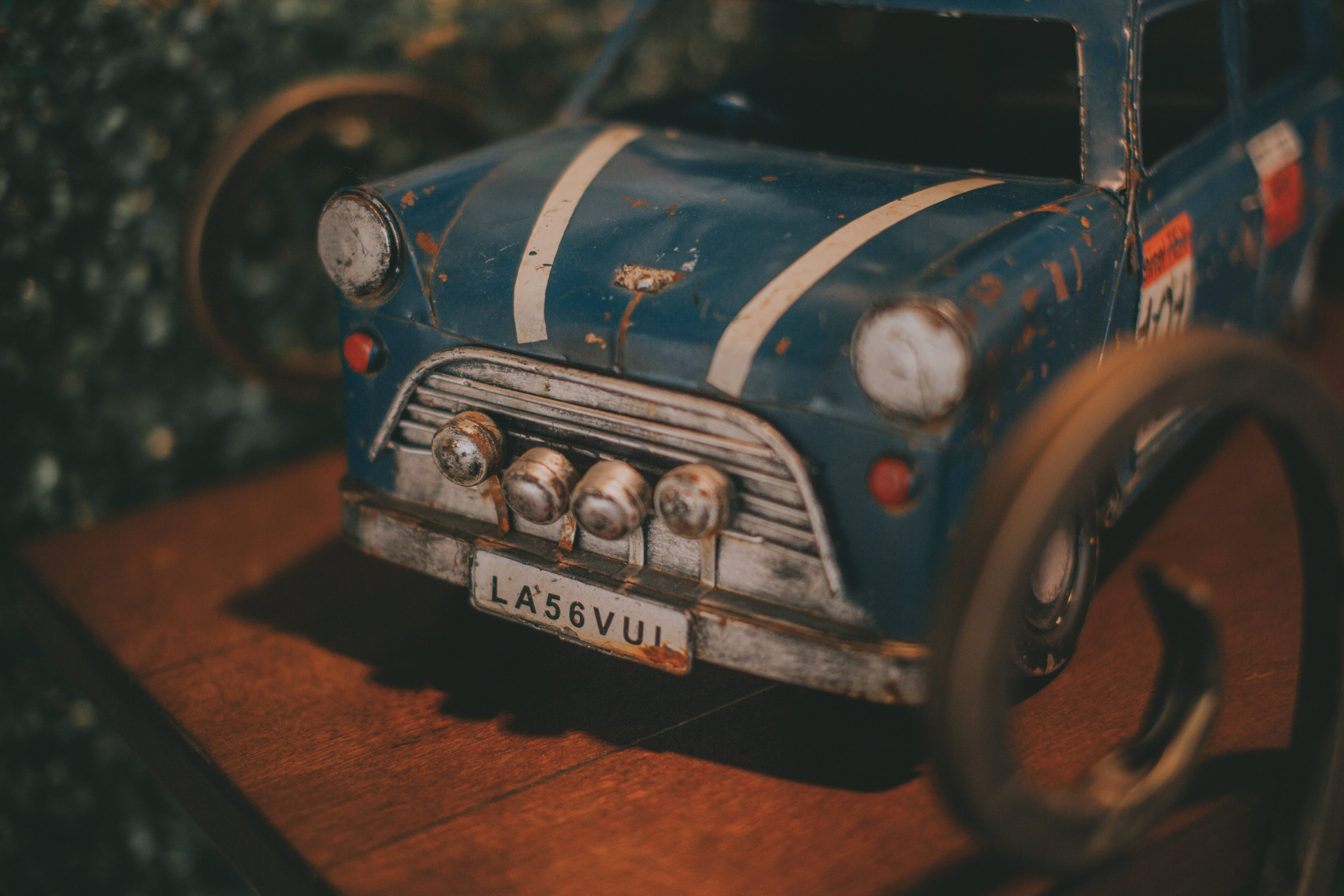 Vintage Minimalist 桌布 壁紙 — 一架帶有白色條紋的褪色藍色復古賽車模型，放置在溫暖燈光下的木質表面上。