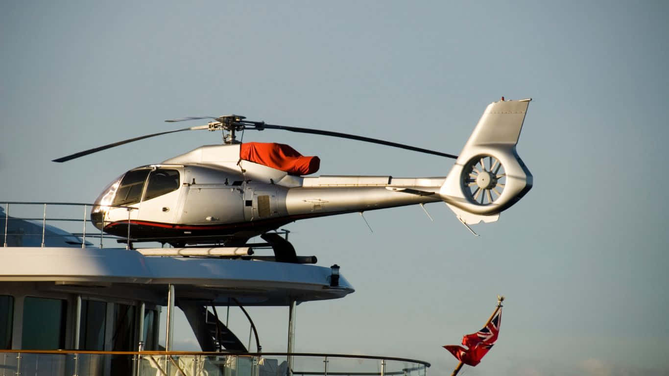 1366x768 Helicopters 桌布 壁紙 — 一架帶有紅色點綴的時尚白色直升機停泊在豪華遊艇上，背景是清澈的藍天。