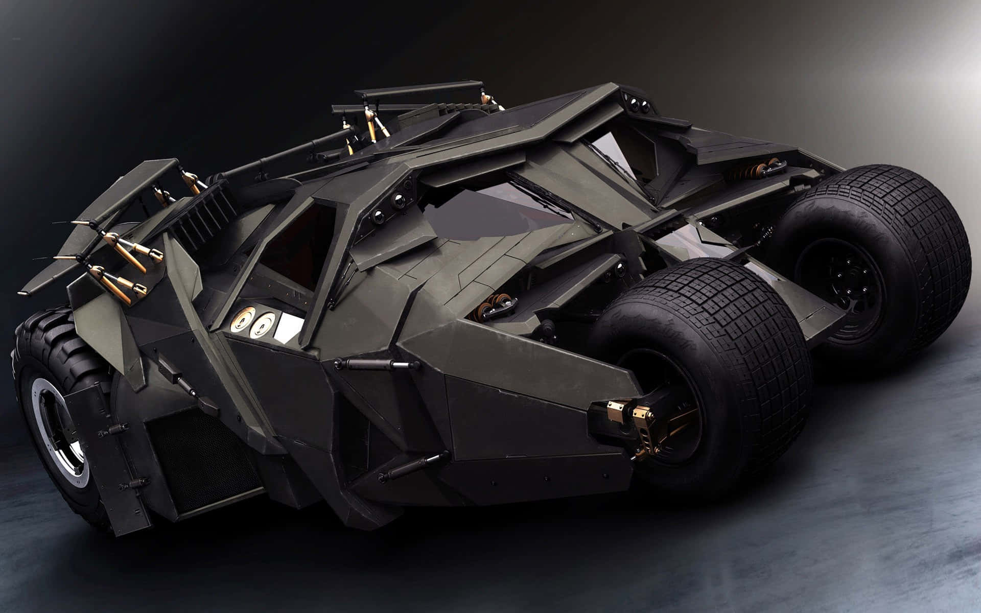 Batmobile Desktop 桌布 壁紙 — 一架帶有金色點綴和巨大輪胎的啞光黑色裝甲蝙蝠車，在黑暗的攝影棚中擺出戲劇性的姿態。