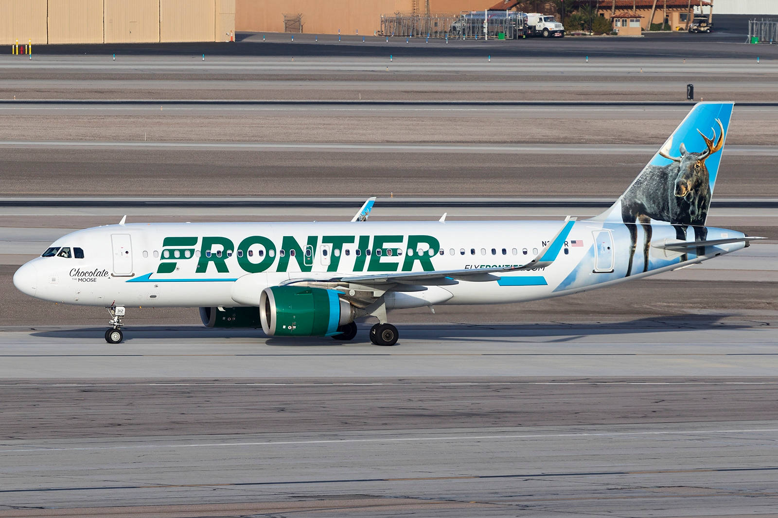  壁紙 — 一架帶有駝鹿塗裝的邊疆航空飛機在明亮的日光下滑行在機場停機坪上。