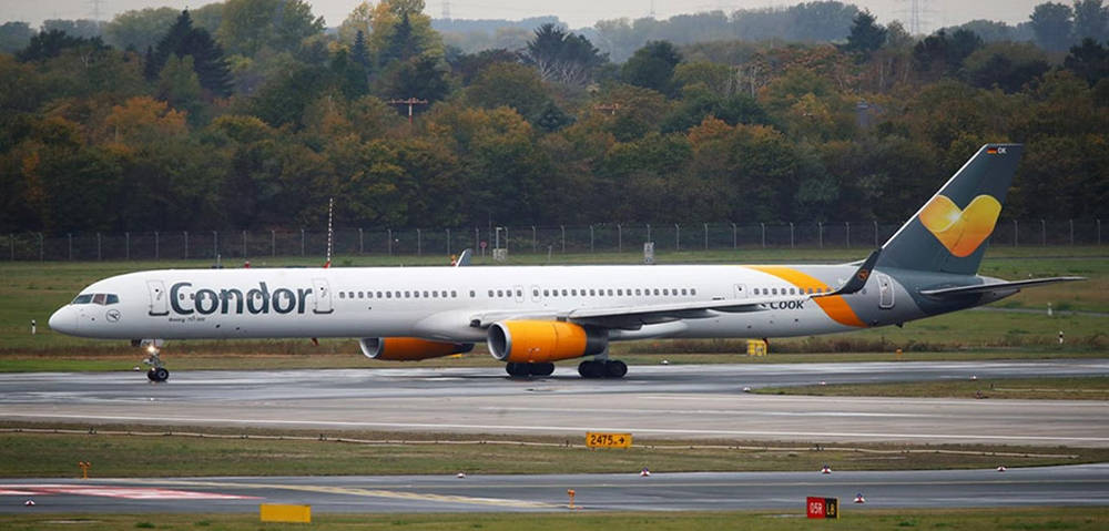 Airport 桌布 壁紙 — 一架康多爾航空的飛機，配備橙色引擎，在潮濕的跑道上滑行，周圍是秋天的樹木。