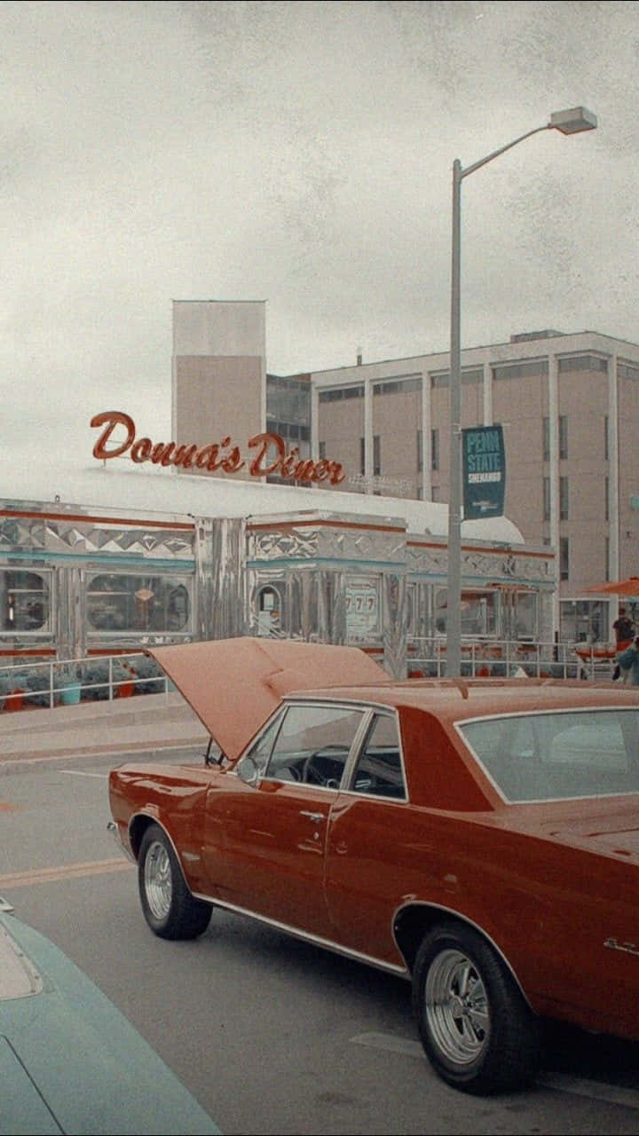 經典汽車 桌布 壁紙 — 一架復古紅色肌肉車打開引擎蓋，停泊在Donna's Diner前，天空多雲。