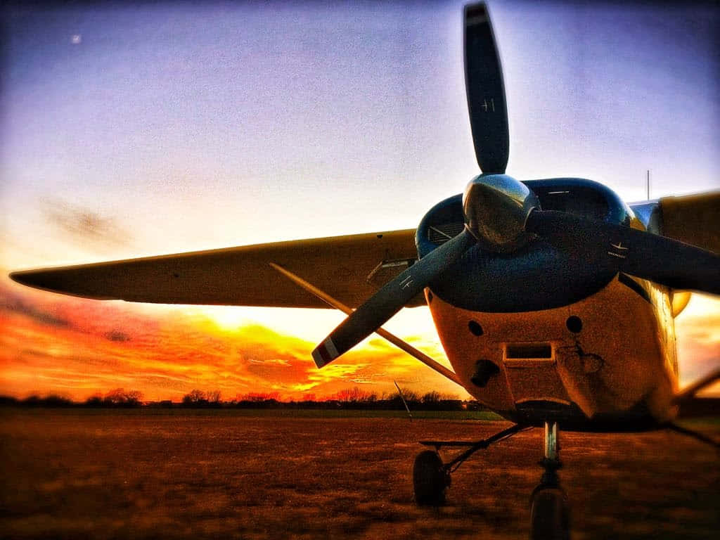 Plane 桌布 壁紙 — 一架復古螺旋槳飛機停在夕陽下的草地上，天空呈現火熱的橙色和紫色。
