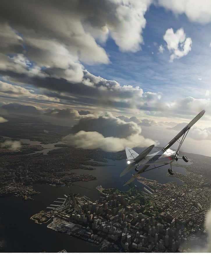 Android Microsoft Flight Simulator 桌布 壁紙 — 一架復古雙翼機在戲劇性的多雲天空下，翱翔於坐落於水道與密集城市擴展之間的廣闊沿海城市上空。