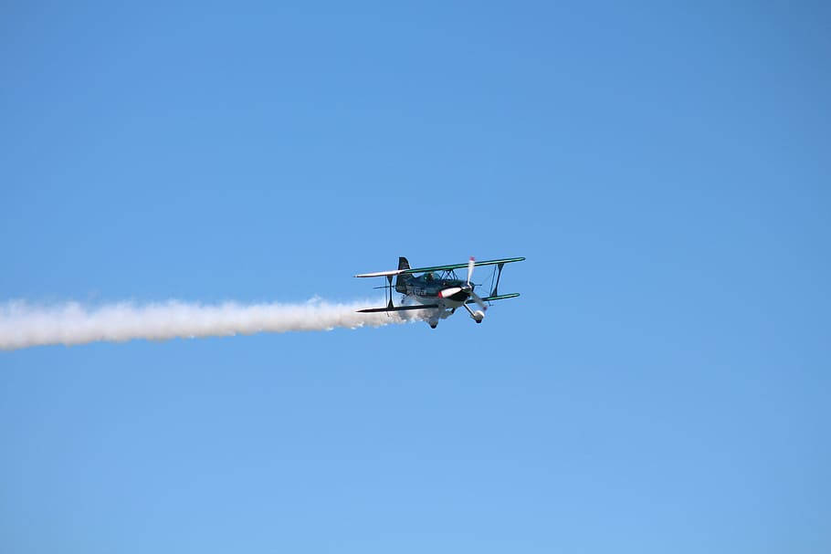Aircraft 桌布 壁紙 — 一架復古雙翼飛機劃過晴朗的藍天，留下濃厚的白色煙霧痕跡。