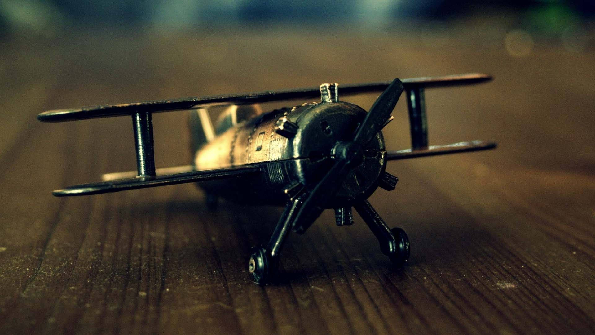 飛機 桌布 壁紙 — 一架復古雙翼飛機模型在溫暖的電影燈光下，放置在風化的木質表面上。