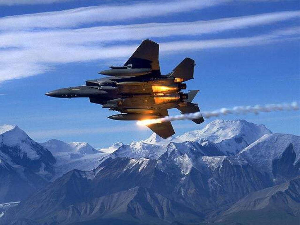 Military Jets 桌布 壁紙 — 一架戰鬥機在白雪覆蓋的山峰上空翱翔，尾焰點燃，映襯著清澈的藍天。