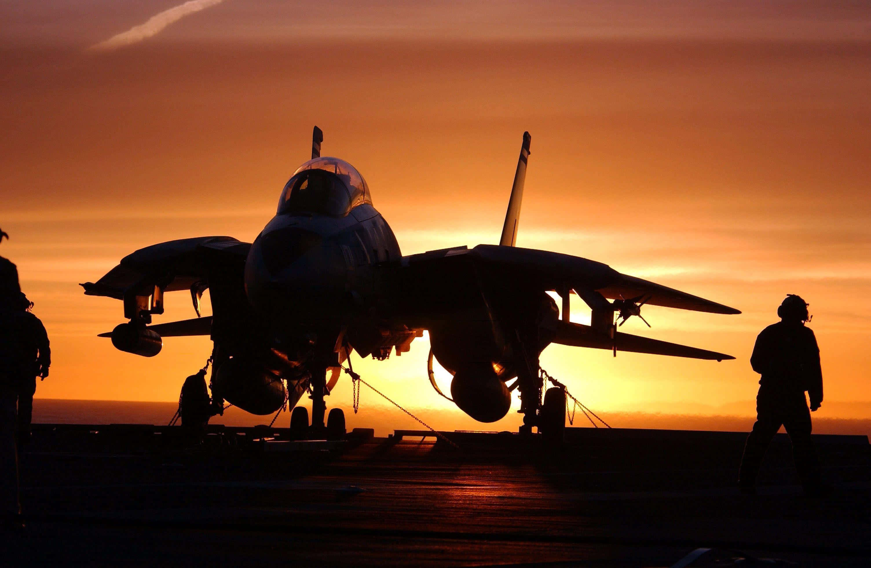 Navy 桌布 壁紙 — 一架戰鬥機在航空母艦甲板上以火紅夕陽為背景形成剪影，附近有船員。