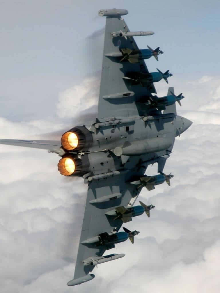 Android Jumbo Jets 桌布 壁紙 — 一架戰鬥機在雲層上方翱翔，加力燃燒室噴射火焰，機翼上掛載飛彈。