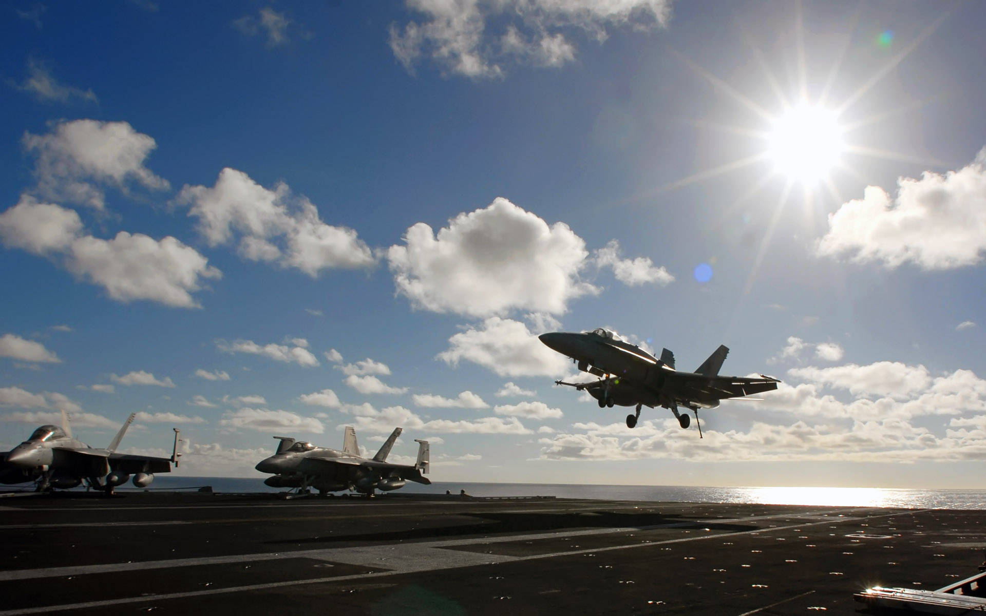 空軍 桌布 壁紙 — 一架戰鬥機從航空母艦甲板起飛，陽光燦爛，雲朵散落，海平線清晰可見。