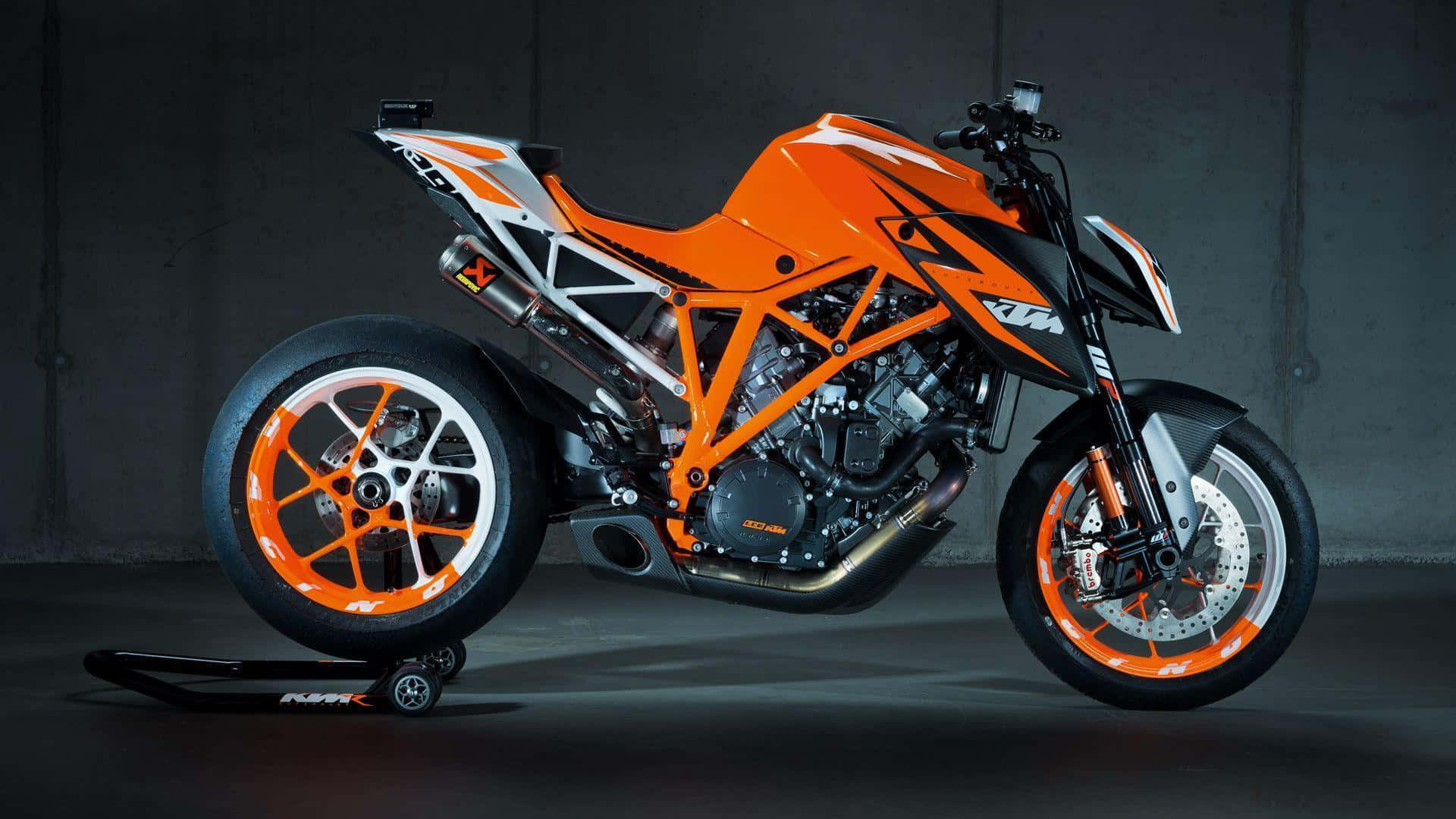 Ktm Bike 桌布 壁紙 — 一架搶眼的橙色和黑色KTM機車，帶有外露車架和訂製輪圈，停放在支架上，背景是深色混凝土牆。