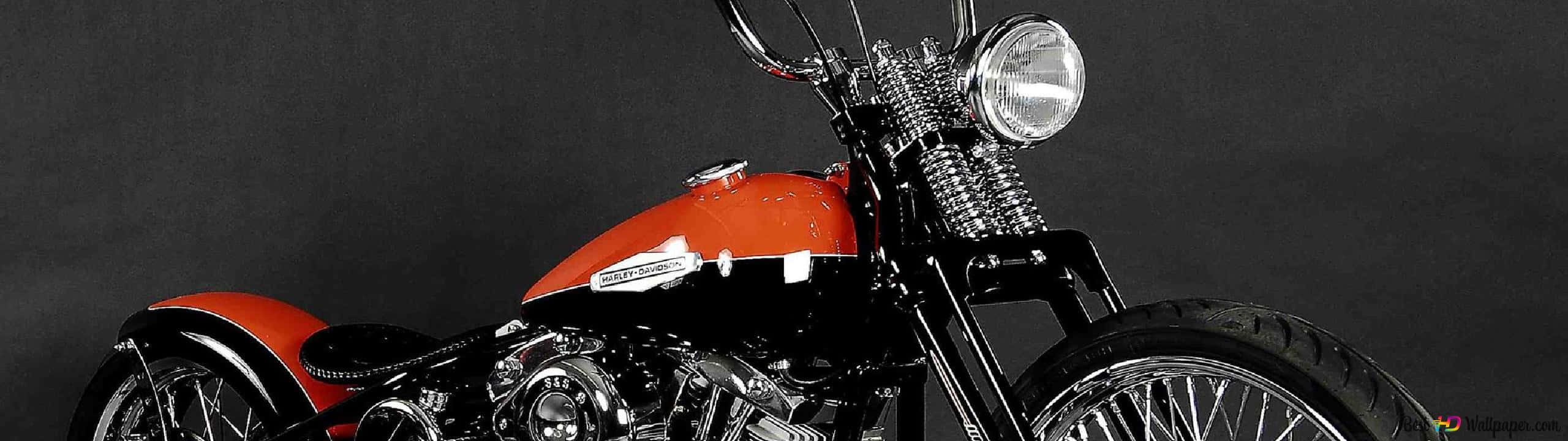 Harley Davidson HD 桌布 壁紙 — 一架搶眼的橙色和黑色定制chopper摩托車，帶有鍍鉻細節，站在深灰色工作室背景前。