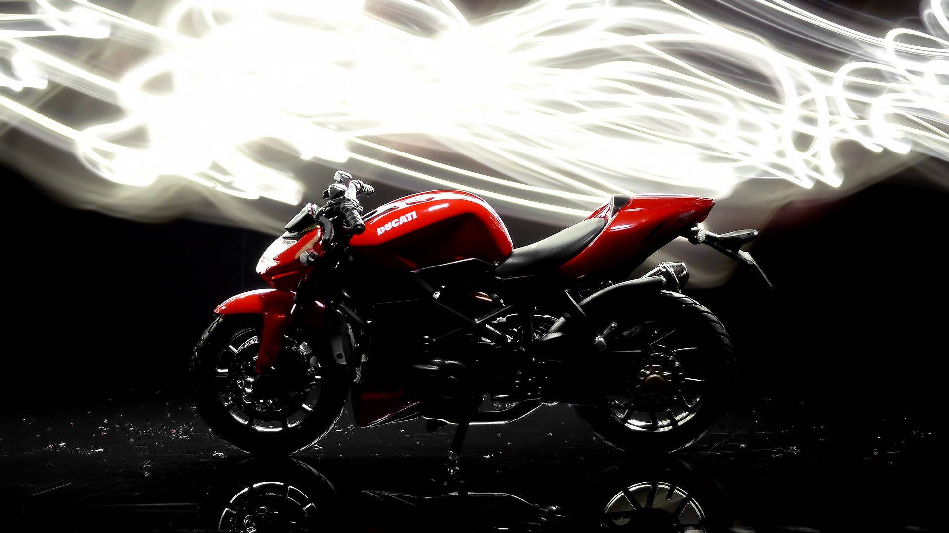機車 桌布 壁紙 — 一架搶眼的紅色Ducati摩托車，在反射黑色表面上，以動態白色光條為背景，蓄勢待發。