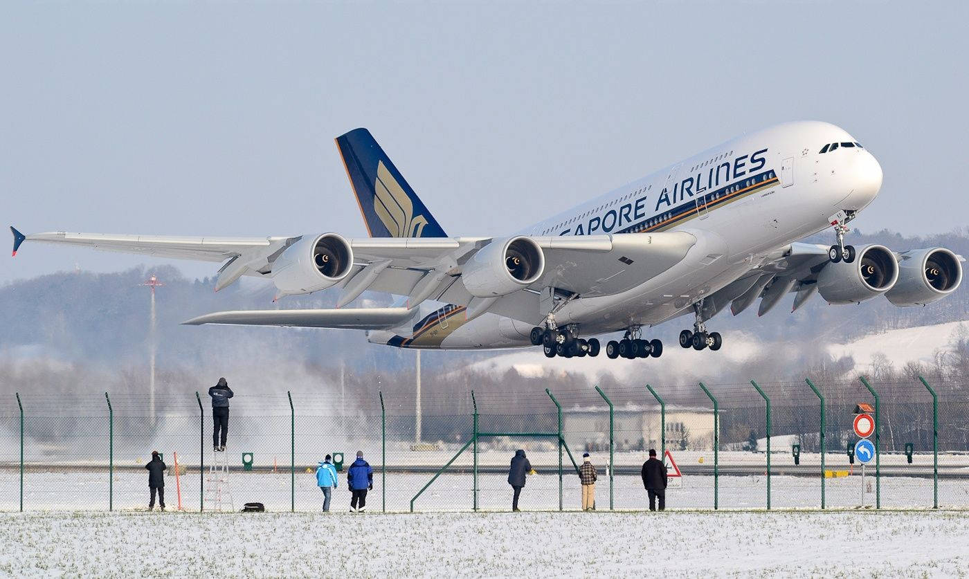 飛機 桌布 壁紙 — 一架新加坡航空的空中巴士A380從積雪跑道起飛，圍觀者在圍欄後觀看。