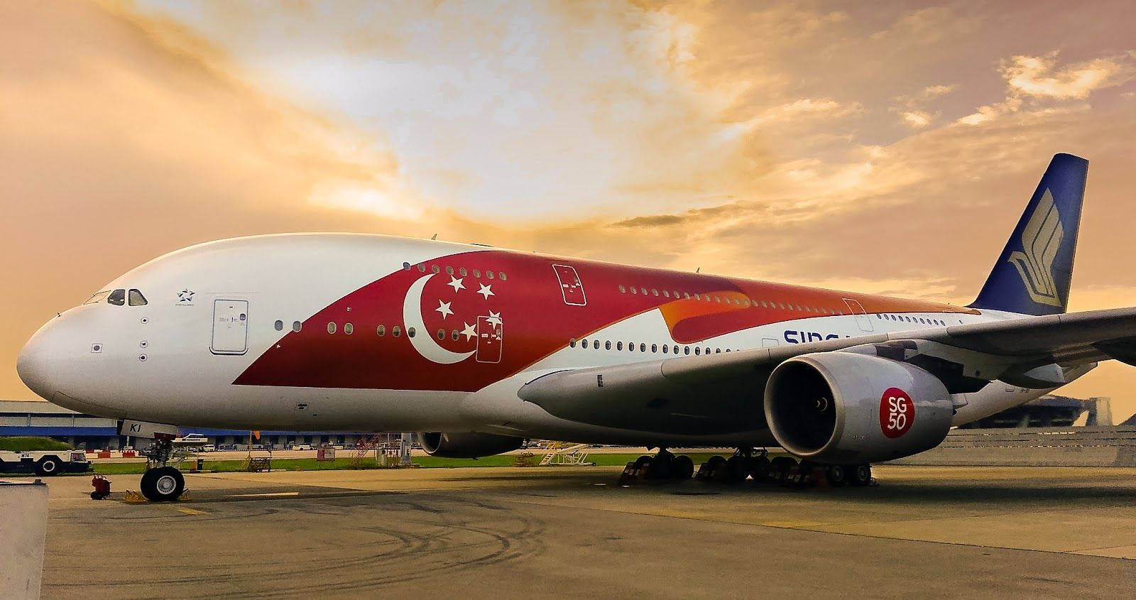 日落 桌布 壁紙 — 一架新加坡航空的空中巴士A380停泊在機場停機坪上，沐浴在金色的夕陽光中，伴隨著戲劇性的雲層。