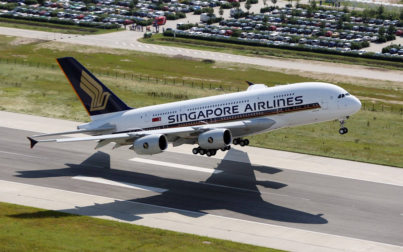 Singapore 桌布 壁紙 — 一架新加坡航空的空中巴士A380正在從跑道起飛，起落架仍然放下，在停機坪上投下長長的影子。