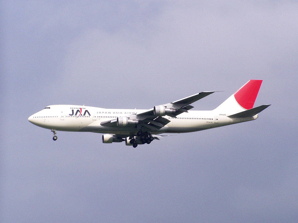 日本 桌布 壁紙 — 一架日本亞洲航空的波音747，白色和紅色塗裝，放下起落架，在暗淡的灰色天空中下降。