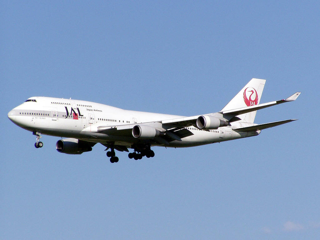 飛機 桌布 壁紙 — 一架日本航空的波音747飛機在晴朗的藍天下下降，起落架已放下。