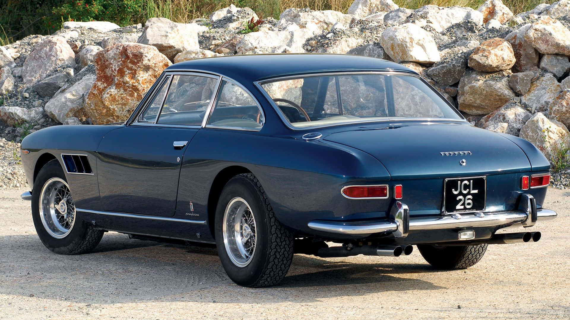 Ferrari 330 桌布 壁紙 — 一架時尚深藍色復古法拉利250 GT停泊在礫石上，旁邊是岩石露頭，在明亮的日光下。