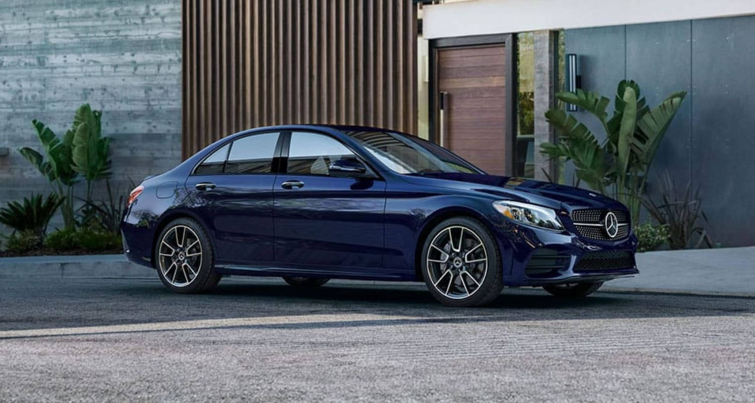 Mercedes Benz C300 桌布 壁紙 — 一架時尚深藍色賓士轎車停放在現代化車道上，旁邊有熱帶植物和時尚房屋。
