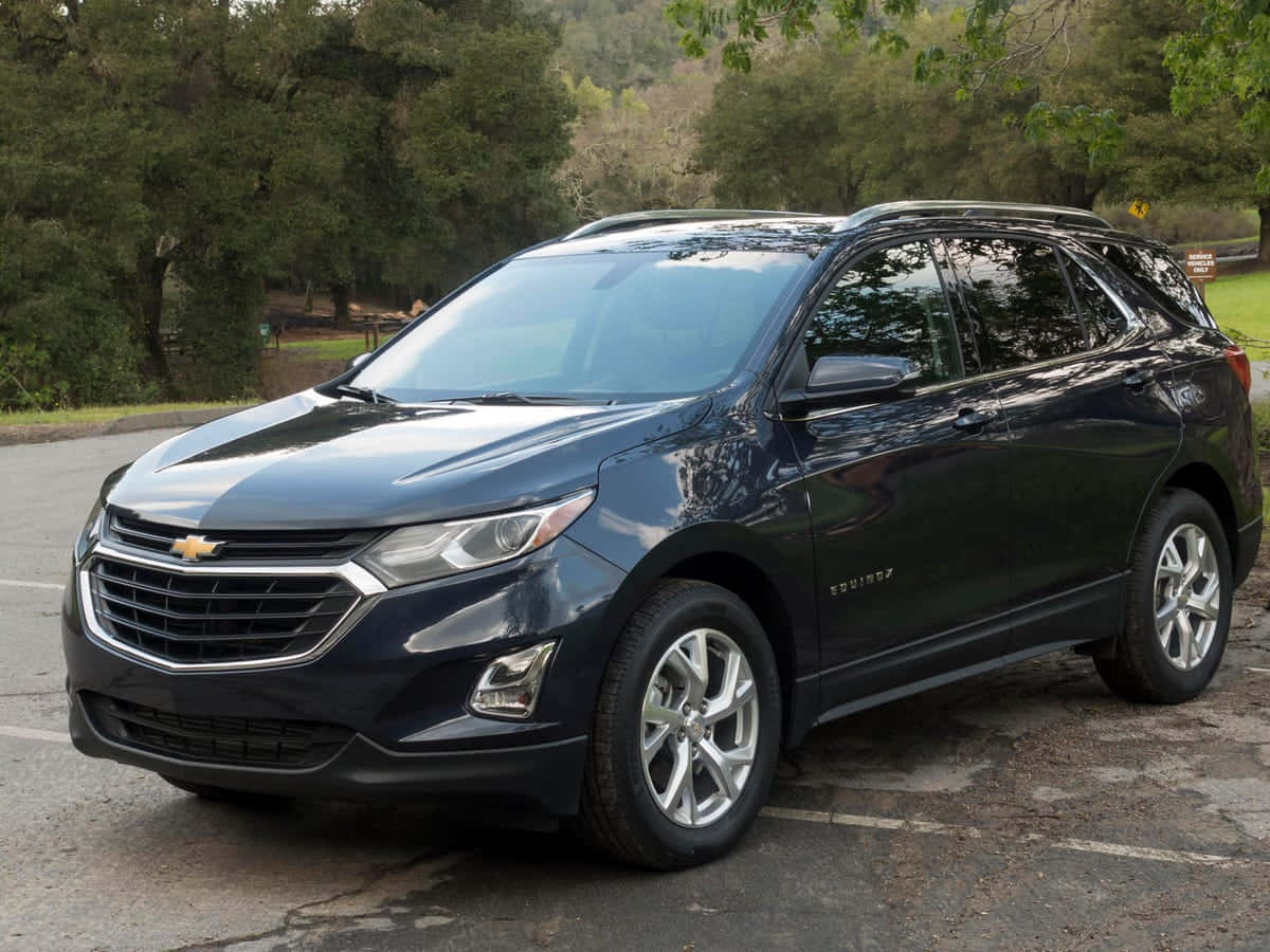 Chevrolet 桌布 壁紙 — 一架時尚深藍色雪佛蘭Equinox SUV停泊在陰涼的停車場，周圍環繞著茂密的綠樹。