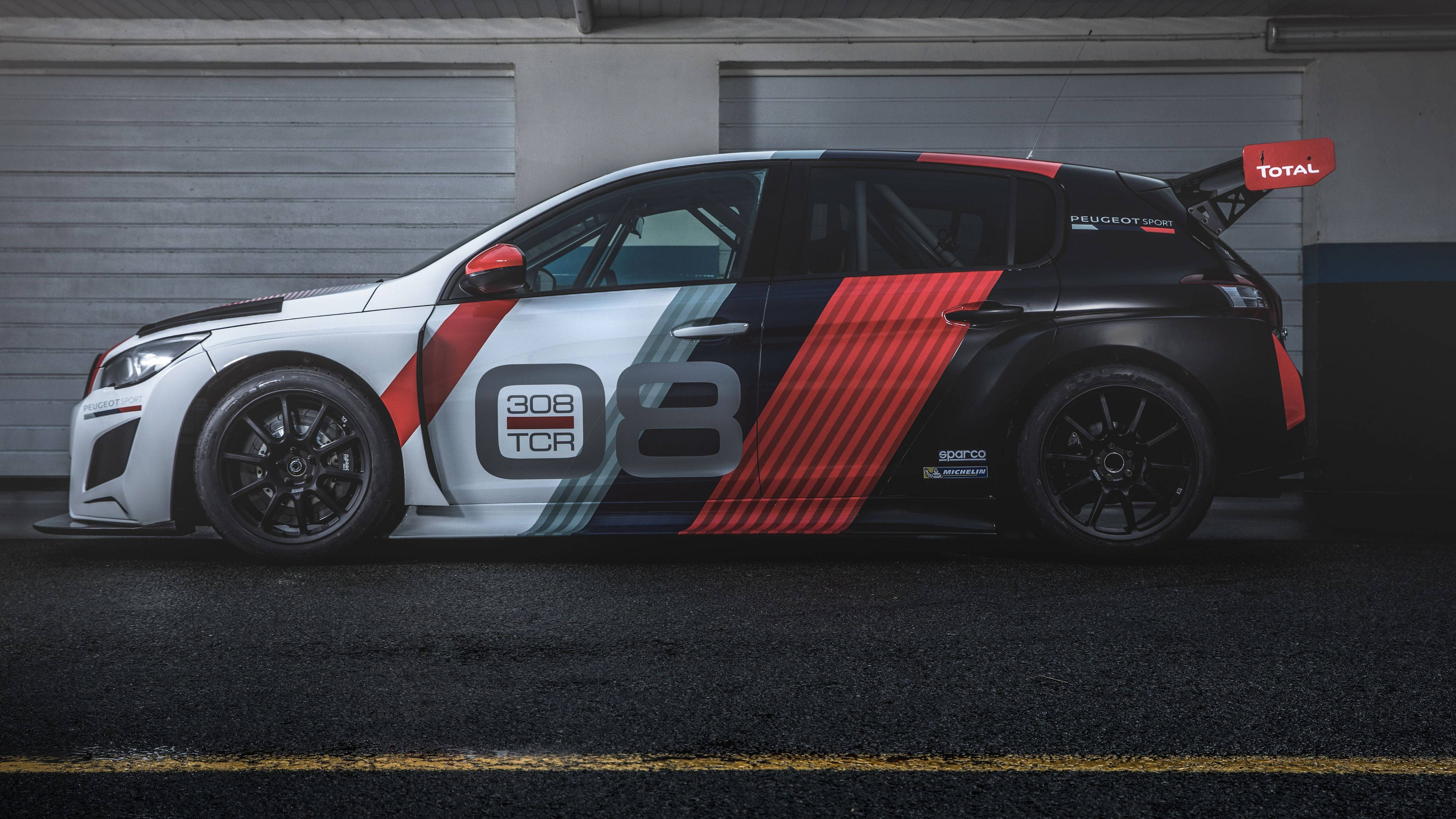 Peugeot 桌布 壁紙 — 一架時尚的Peugeot 308 TCR賽車，帶有醒目的紅、黑、白塗裝，在車庫中蓄勢待發，準備比賽。