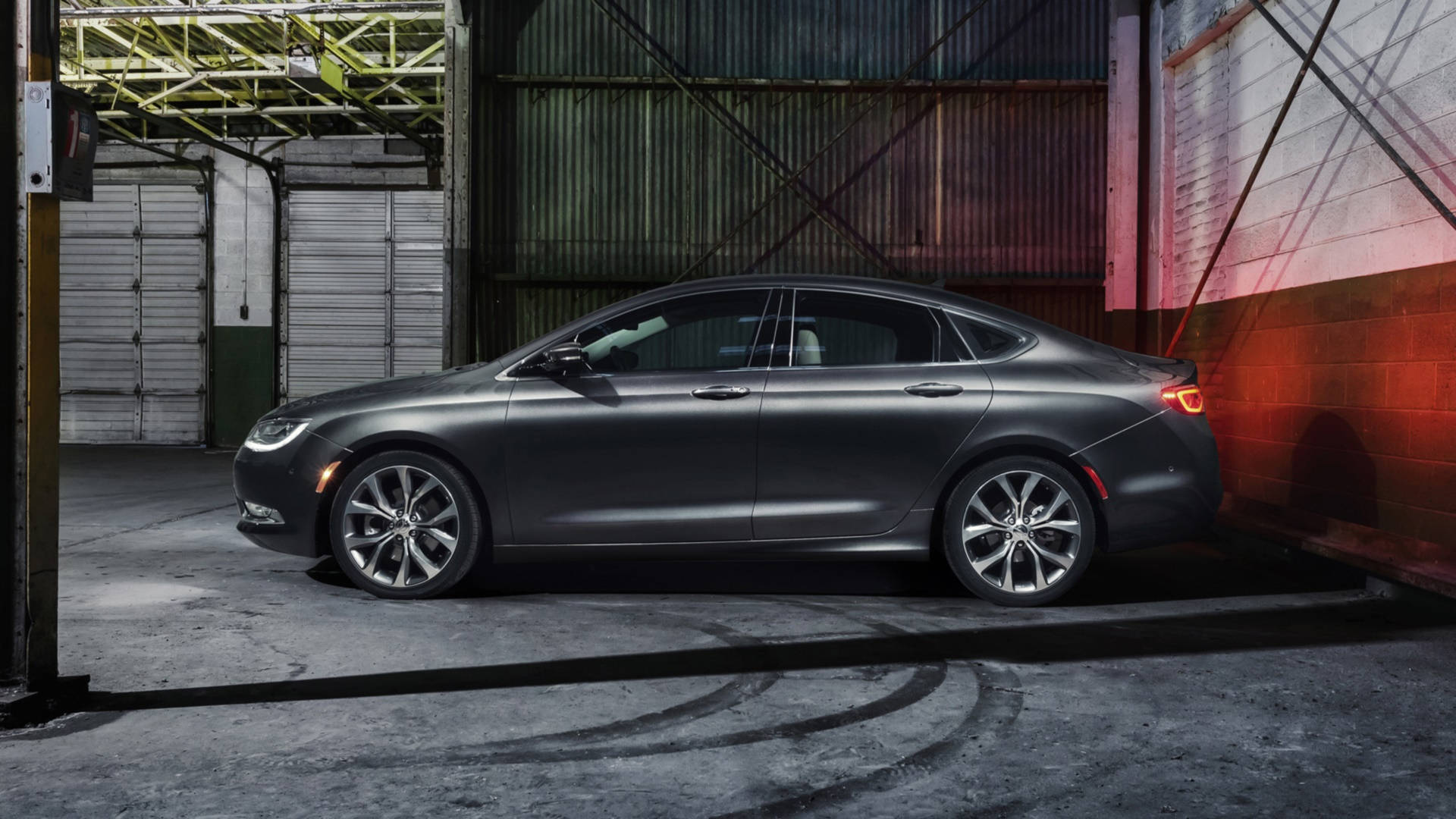 Chrysler 桌布 壁紙 — 一架時尚的啞光灰色轎車停放在粗糙的工業車庫中，紅色牆壁燈光投射出戲劇性的陰影。
