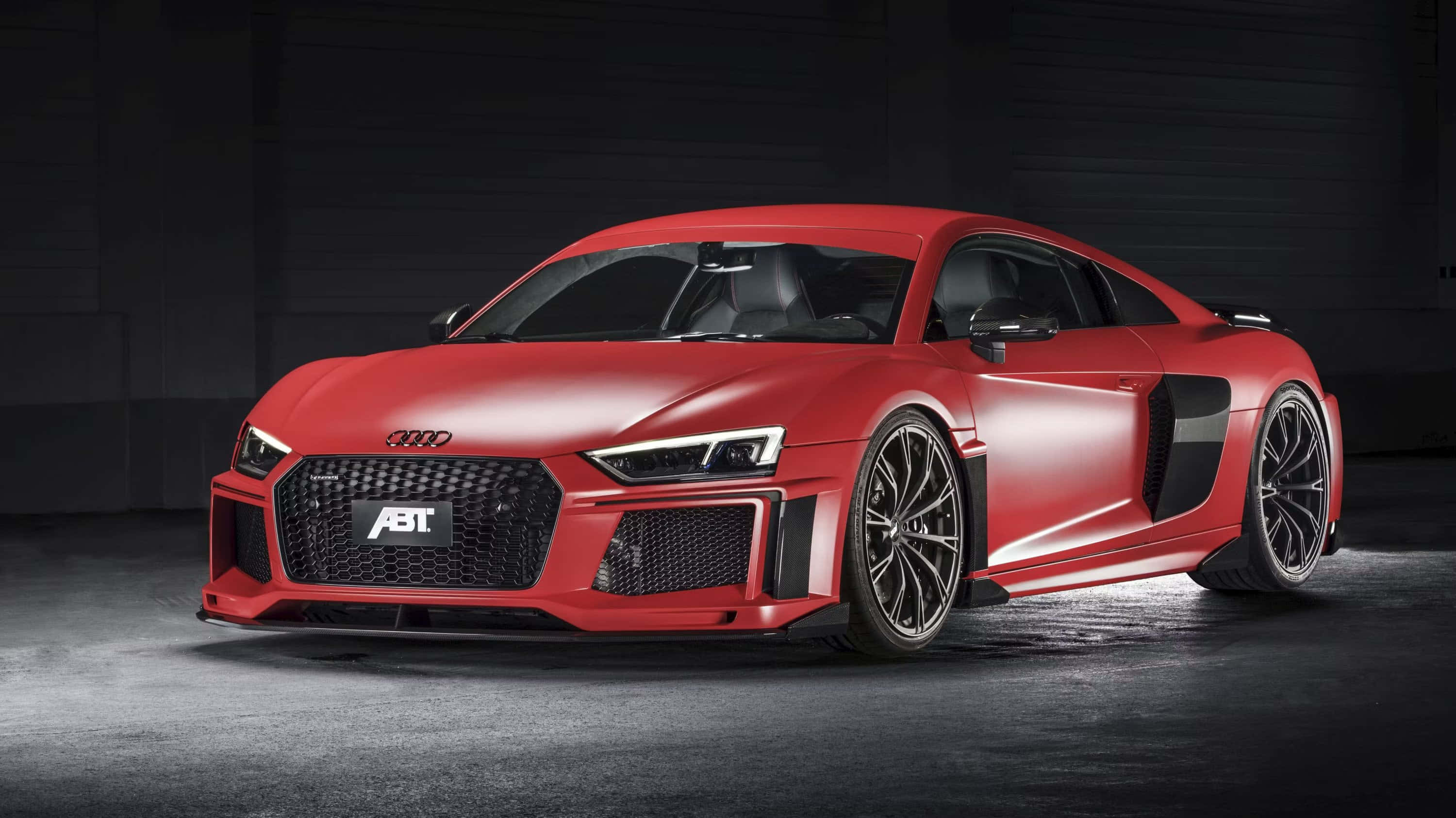 奧迪R8 桌布 壁紙 — 一架時尚的啞光紅色ABT Audi R8跑車在黑暗的工業車庫中被聚光燈戲劇性地照亮。