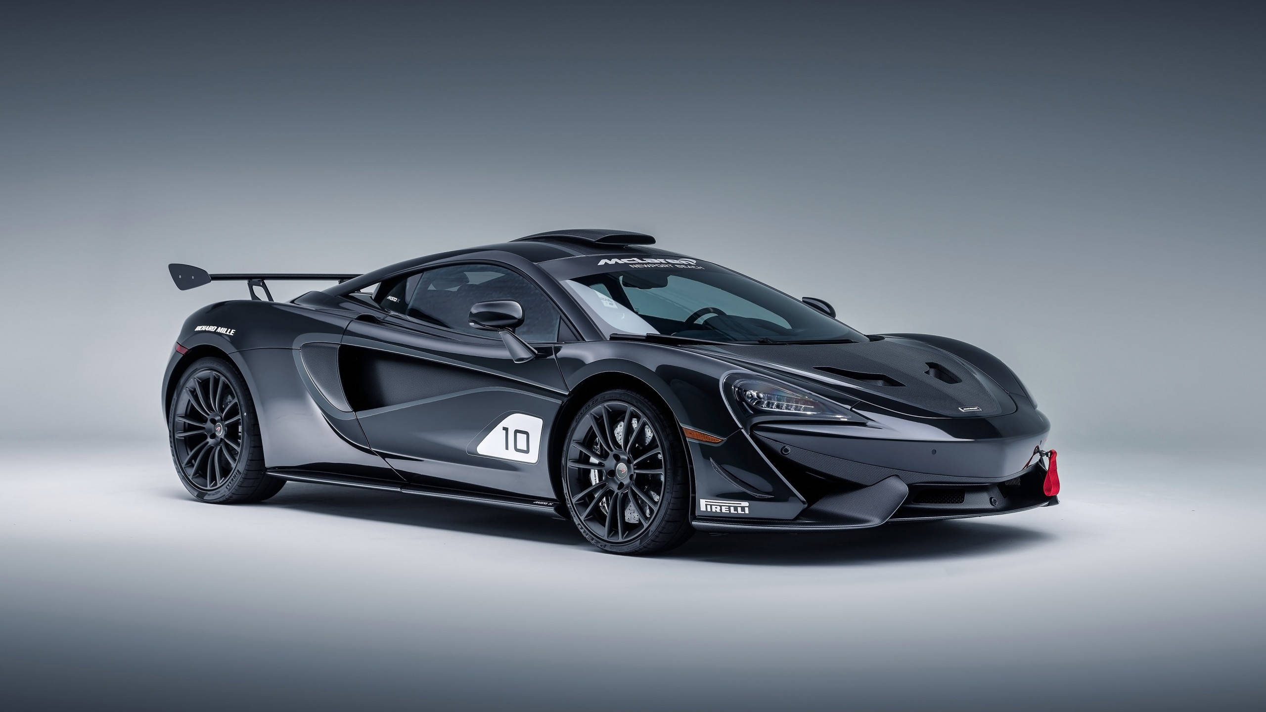 高清汽車 桌布 壁紙 — 一架時尚的啞光黑色McLaren 650S GT3賽車，帶有10號和Pirelli品牌標誌，擺放在漸變灰色工作室背景前。