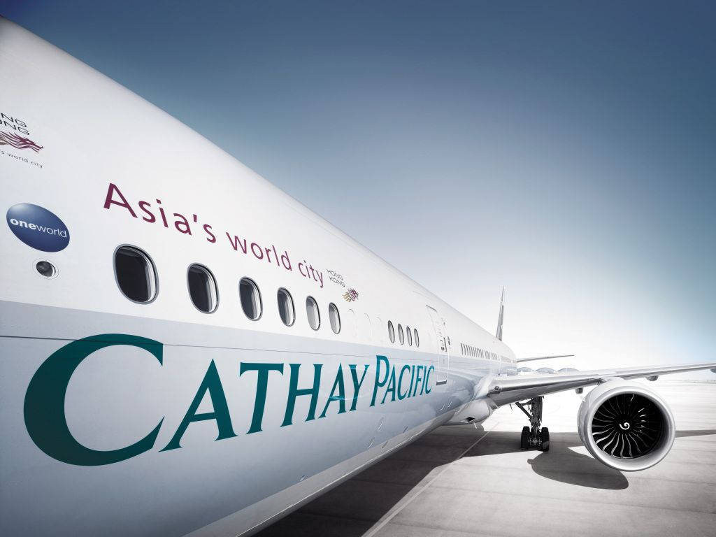 Airport 桌布 壁紙 — 一架時尚的國泰航空飛機在晴朗藍天下停泊在陽光普照的停機坪上，機身上可見大膽的品牌標誌。