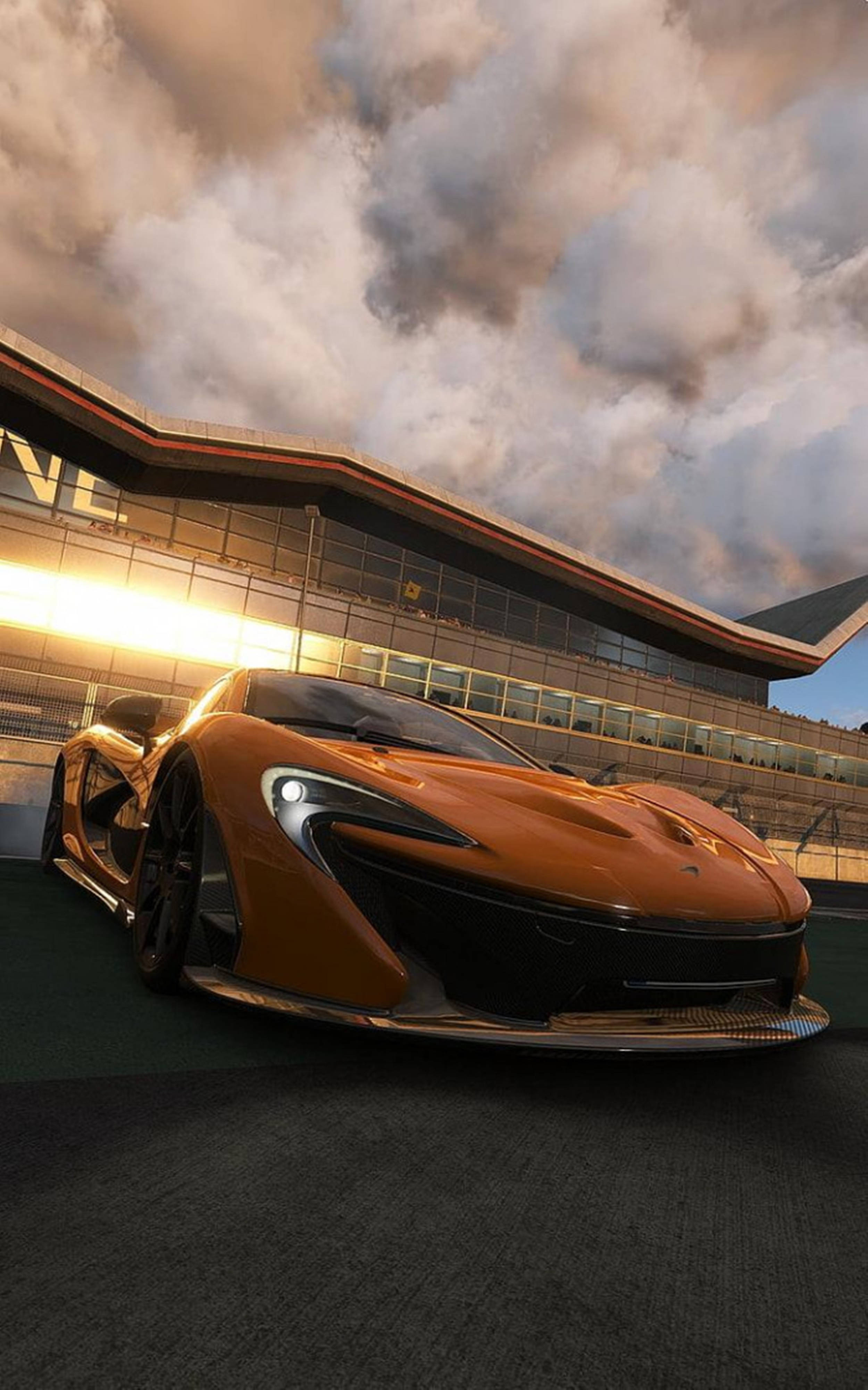 Luxury 桌布 壁紙 — 一架時尚的橙色McLaren跑車在現代賽道建築旁，於金色夕陽下閃閃發光。