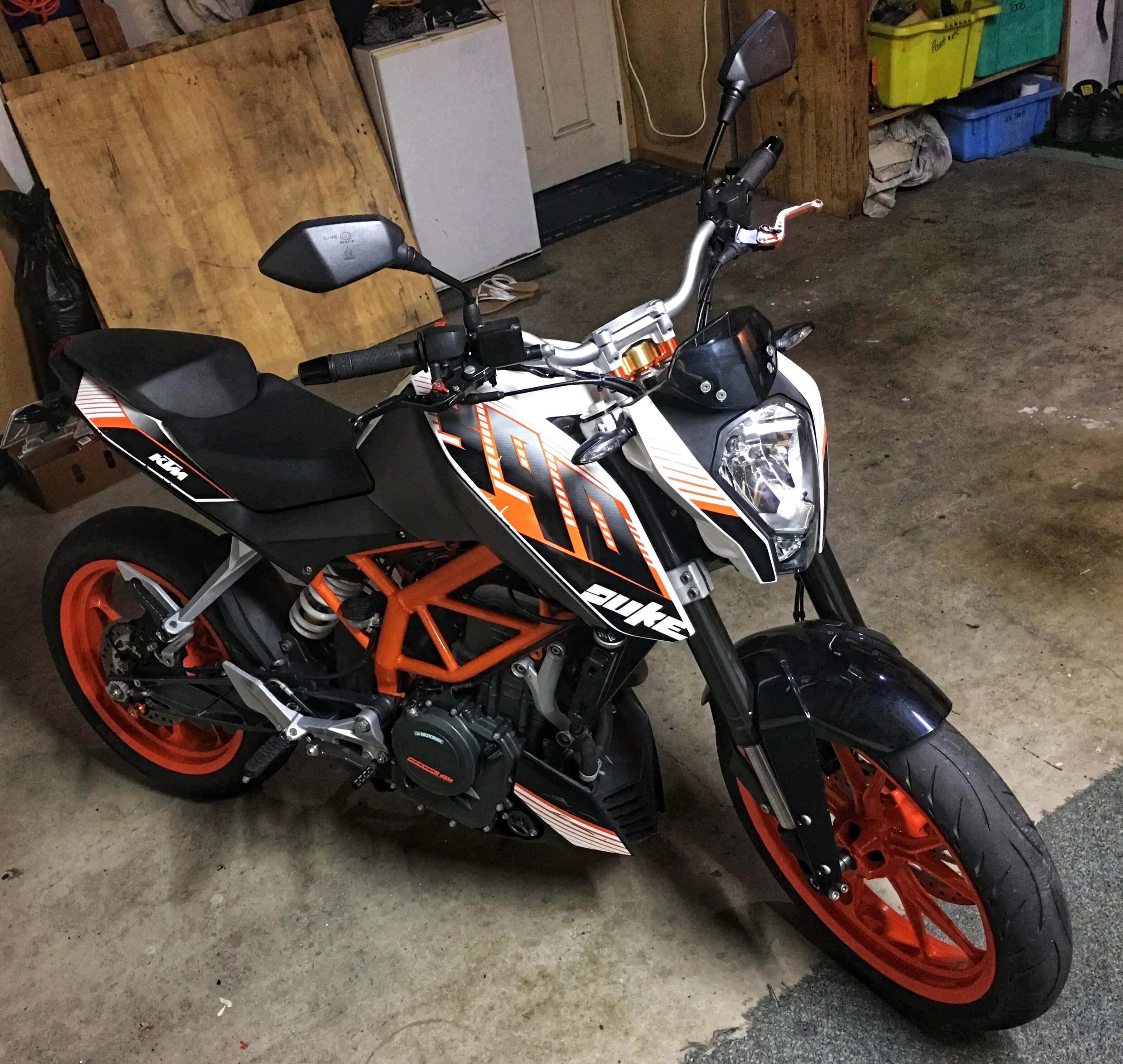 Garage 桌布 壁紙 — 一架時尚的橙色和黑色KTM Duke機車停放在一個混凝土地板和木牆的雜亂車庫內。