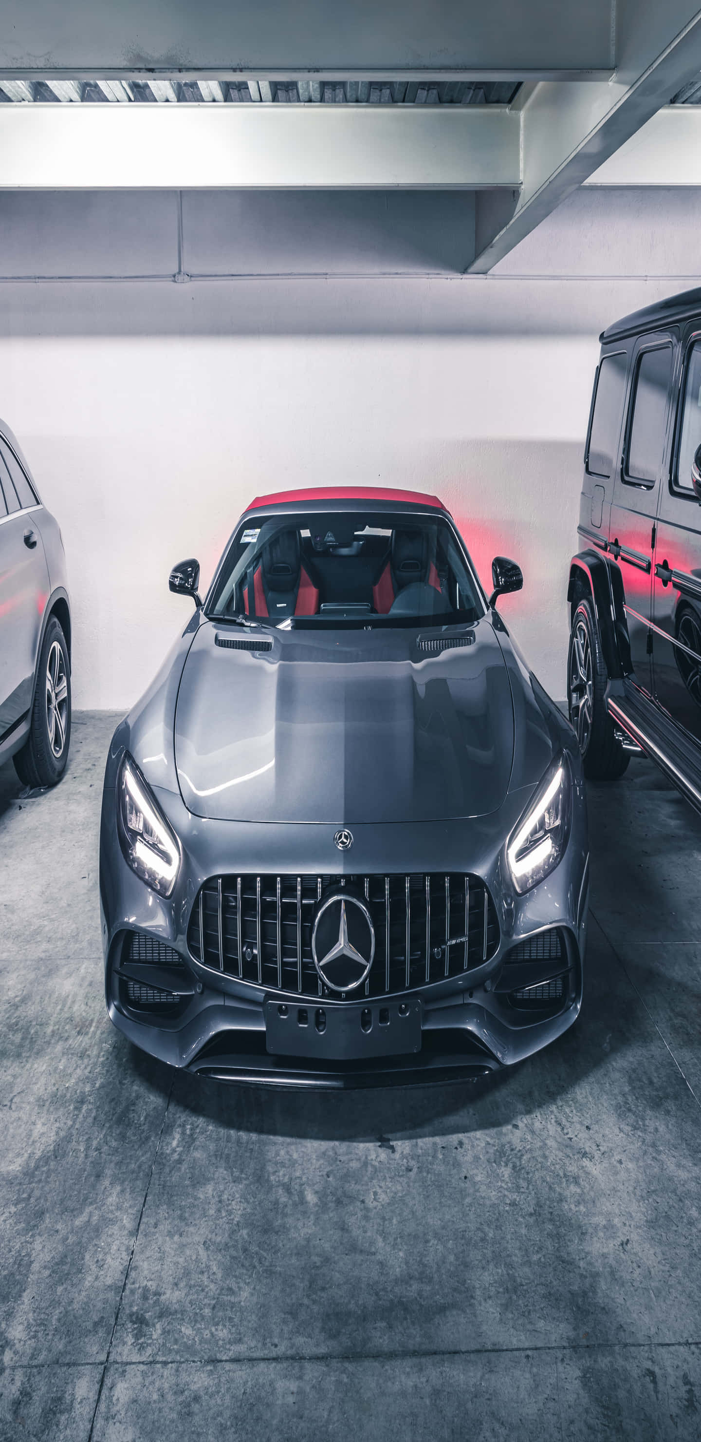 Cool Car 桌布 壁紙 — 一架時尚的灰色 Mercedes-AMG 跑車帶有紅色點綴，停泊在現代車庫中，旁邊是一輛黑色 SUV。