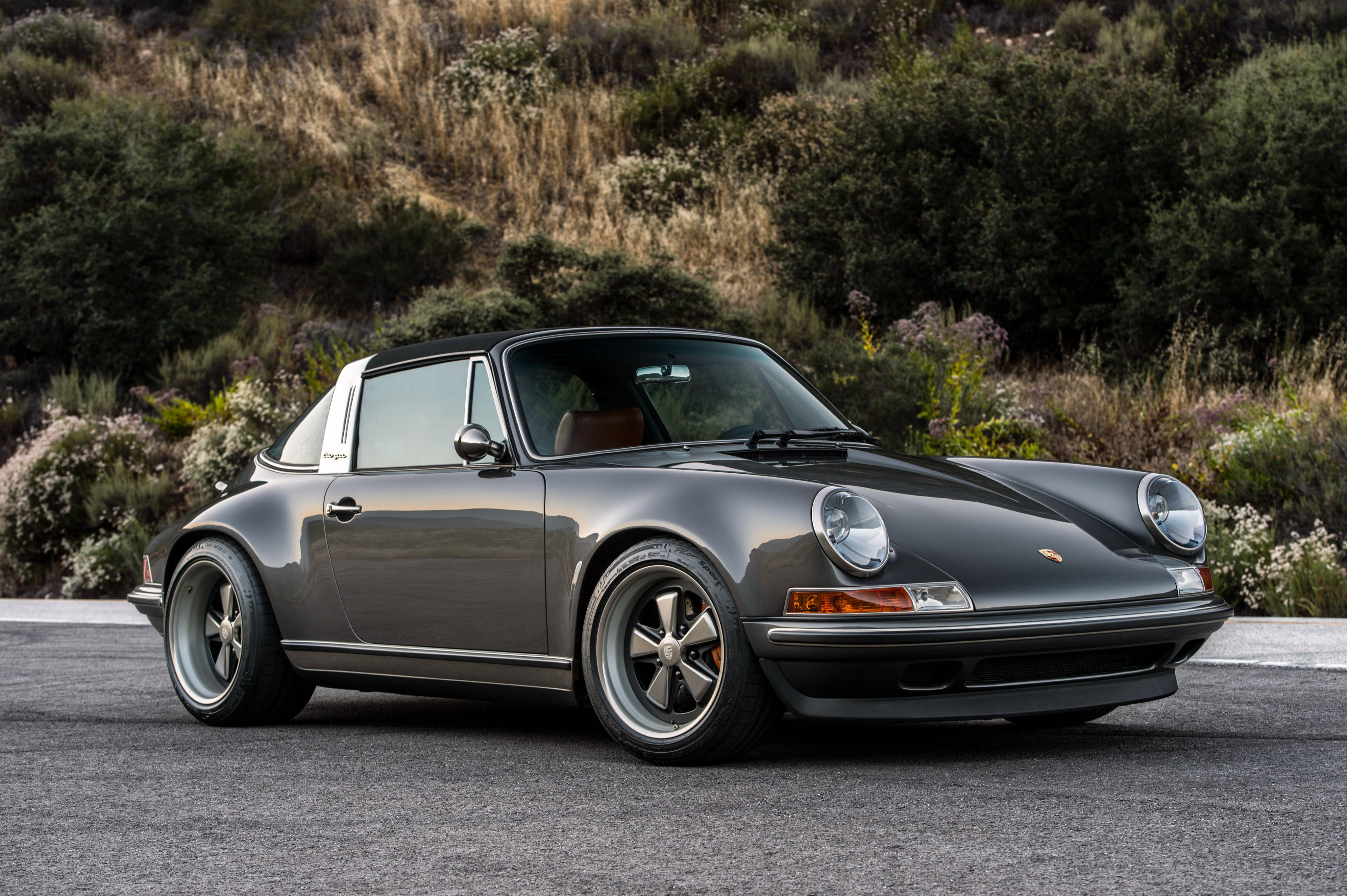 Singer 桌布 壁紙 — 一架時尚的灰色保時捷911 Targa停在瀝青路上，背景有乾燥的灌木和綠色灌木。