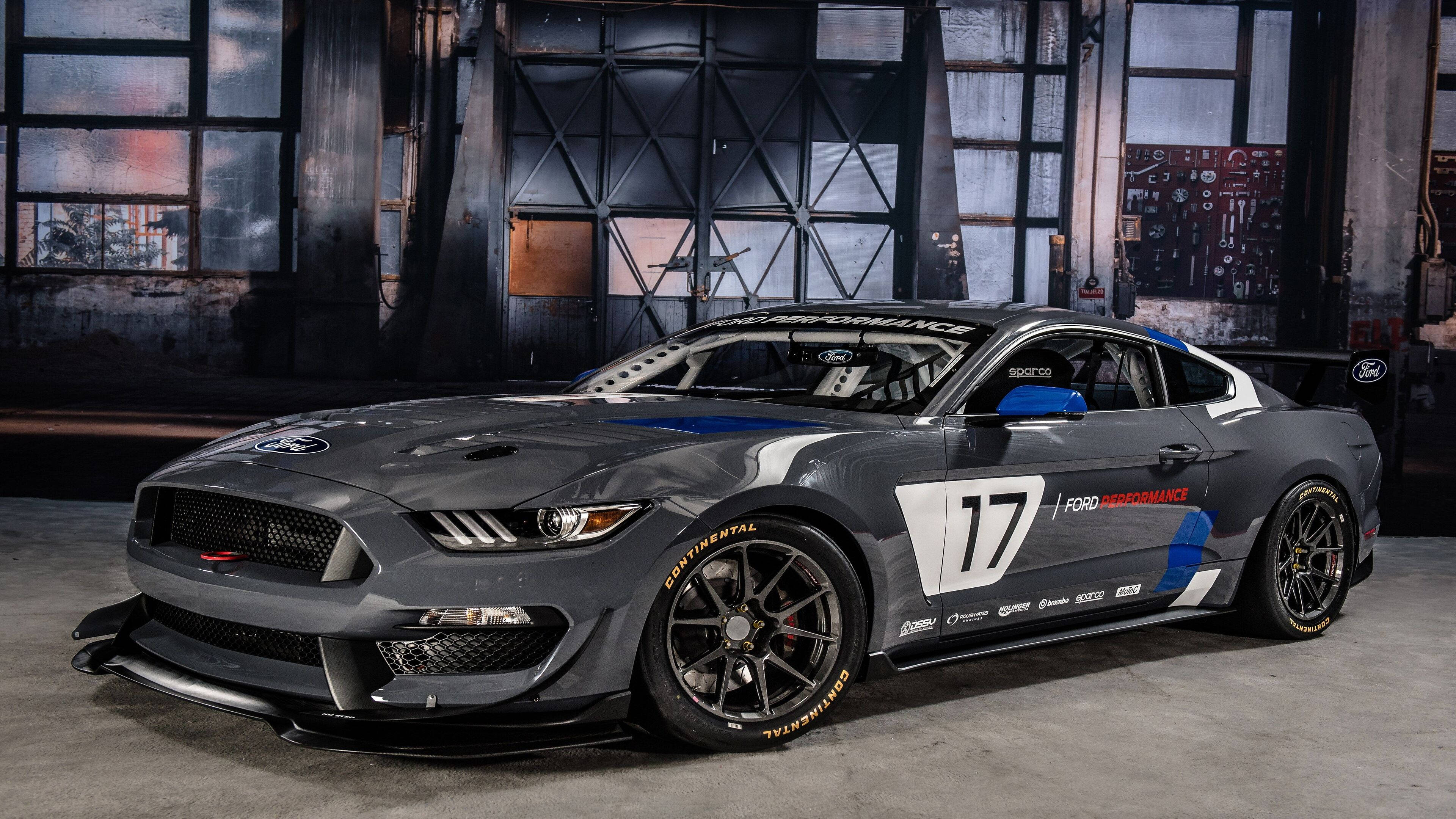 mustang HD 桌布 壁紙 — 一架時尚的灰色福特野馬賽車，號碼17，停放在一個帶有大窗戶的骯髒工業倉庫內。