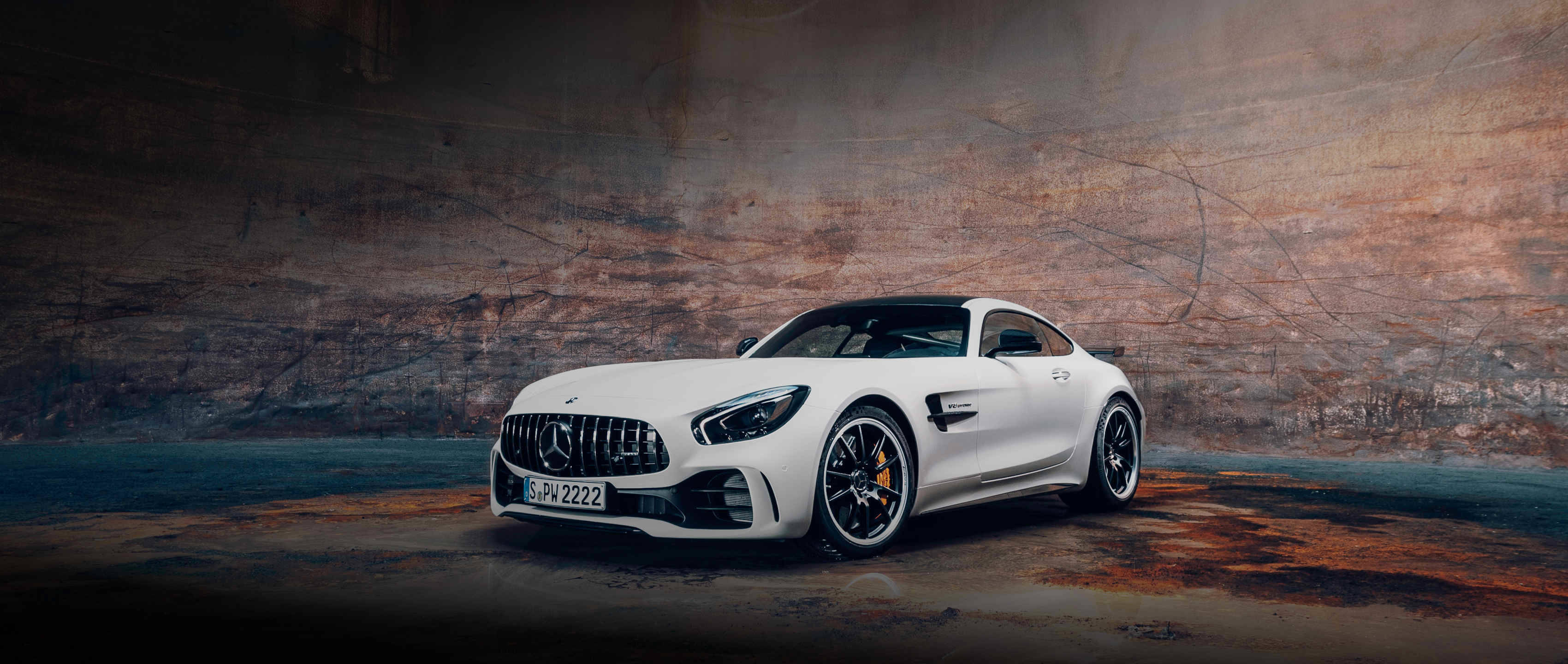 Amg 桌布 壁紙 — 一架時尚的白色 Mercedes-AMG GT 停放在粗糙的工業隧道中，帶有戲劇性的燈光。