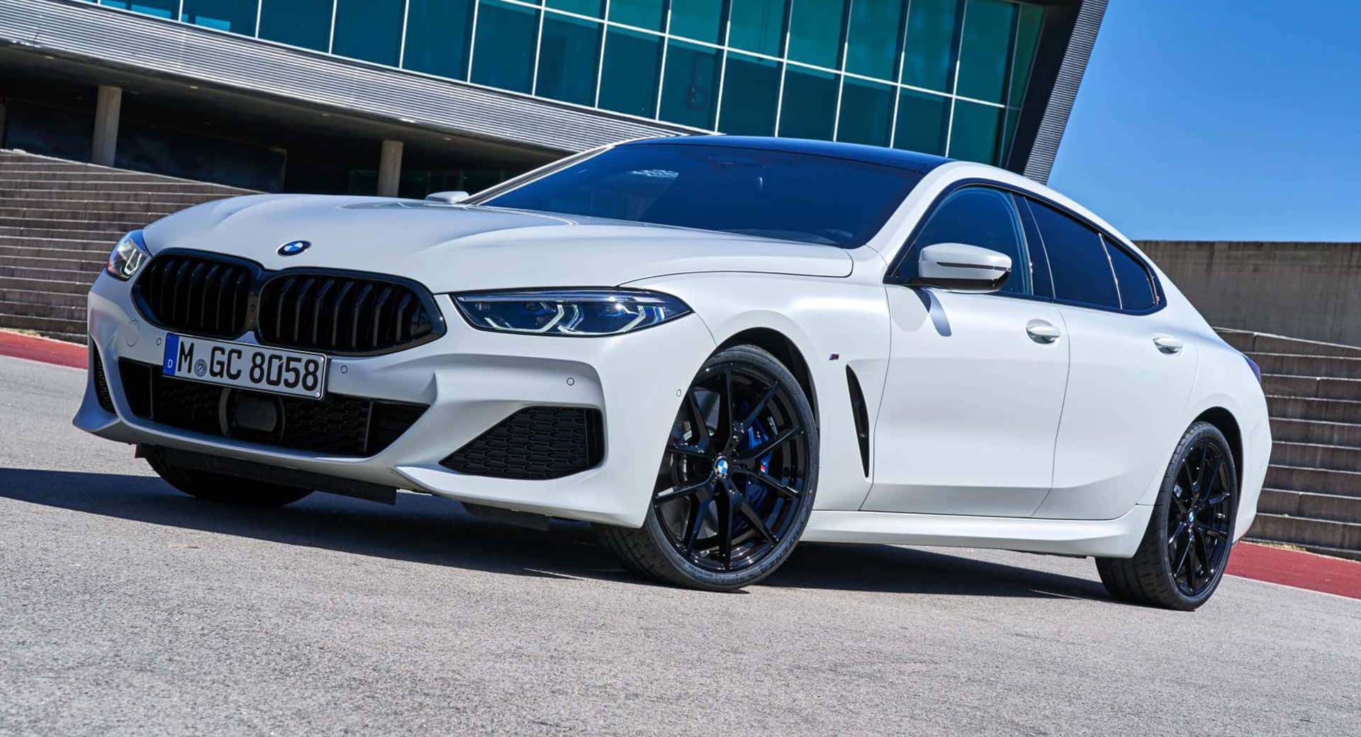Bmw 8 Series 桌布 壁紙 — 一架時尚的白色BMW 8系列轎跑車停在柏油路上，背景是現代玻璃建築，天空清澈湛藍。