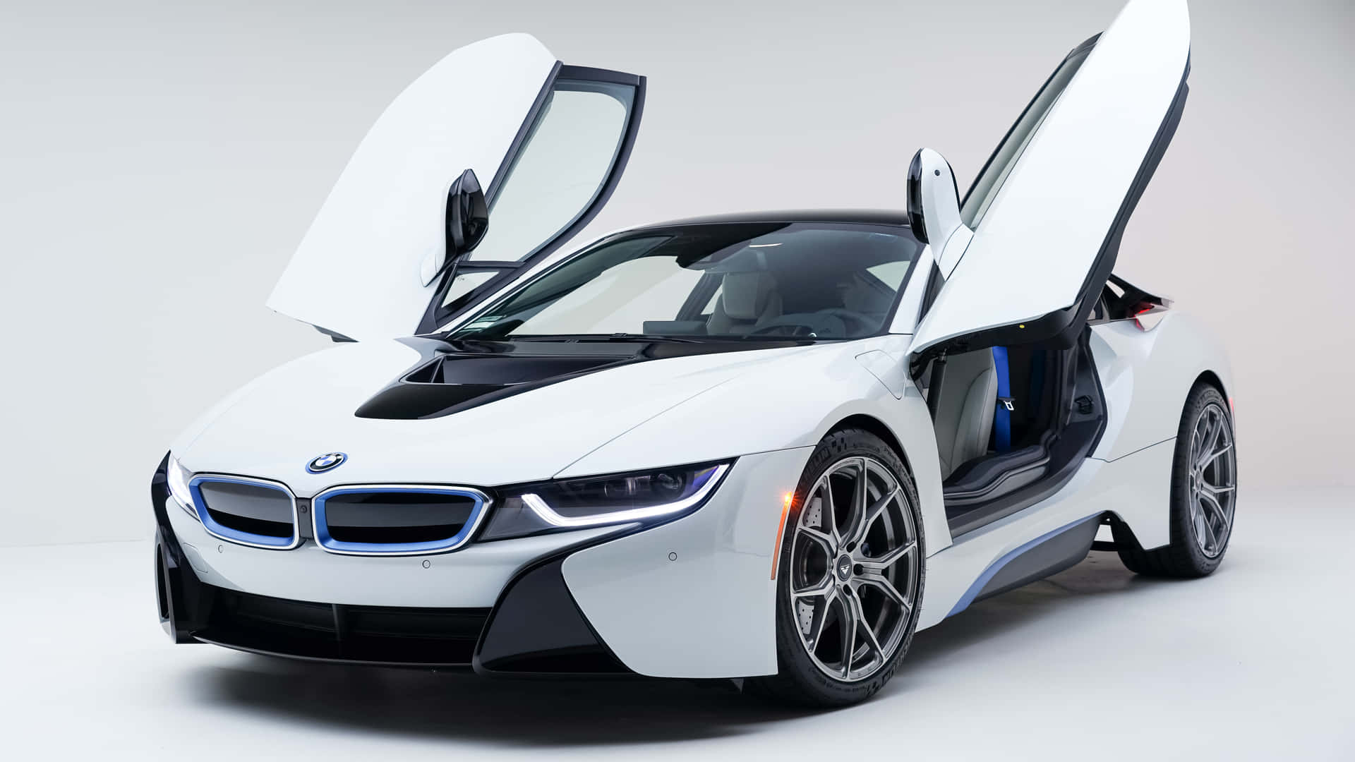 BMW 動圖 桌布 壁紙 — 一架時尚的白色BMW i8跑車，鷗翼門打開，背景是簡約的工作室。