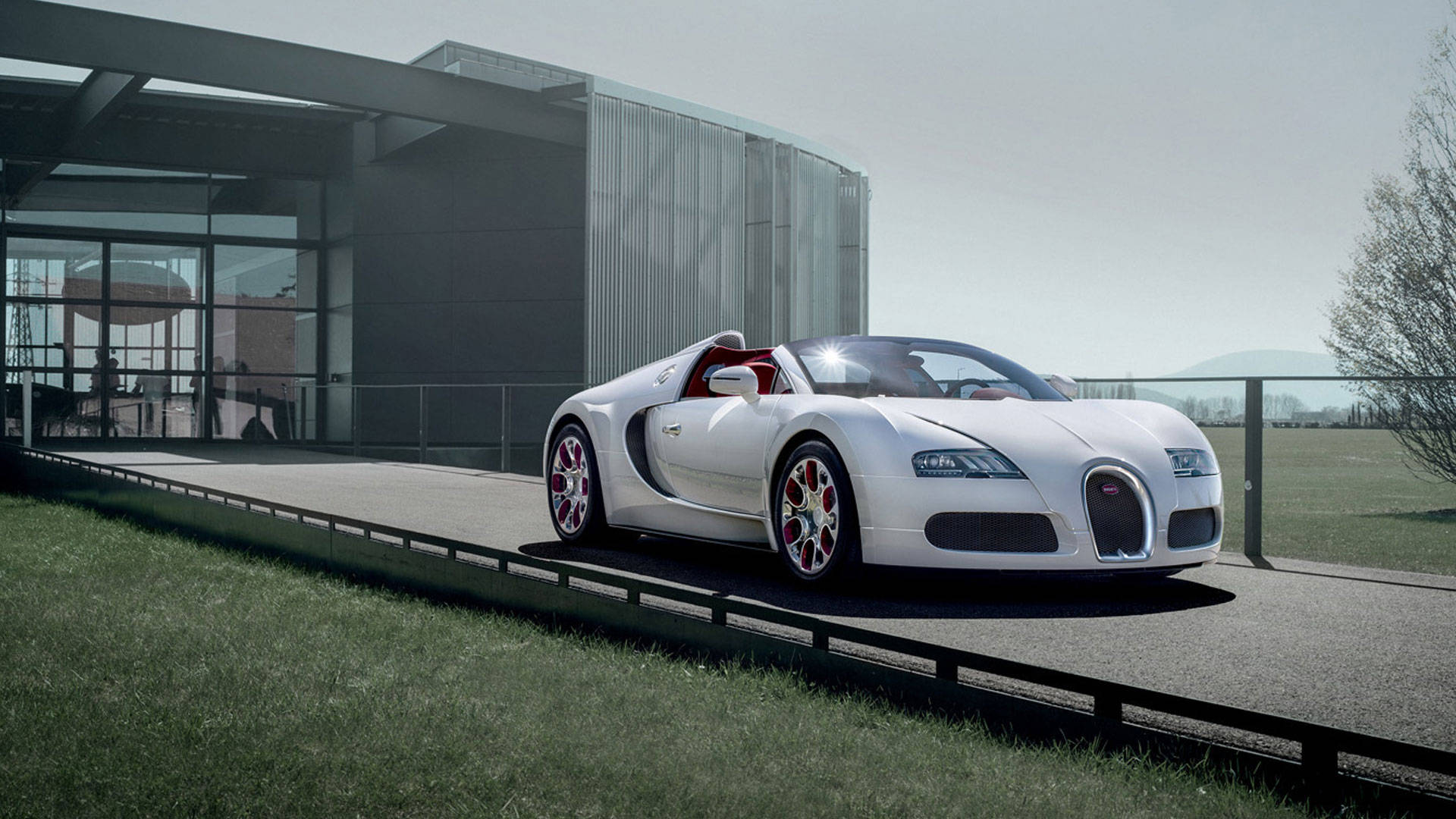Cool Bugatti 桌布 壁紙 — 一架時尚的白色Bugatti Veyron跑車，配備紅色內裝和輪圈，停放在玻璃建築旁的現代化車道上。