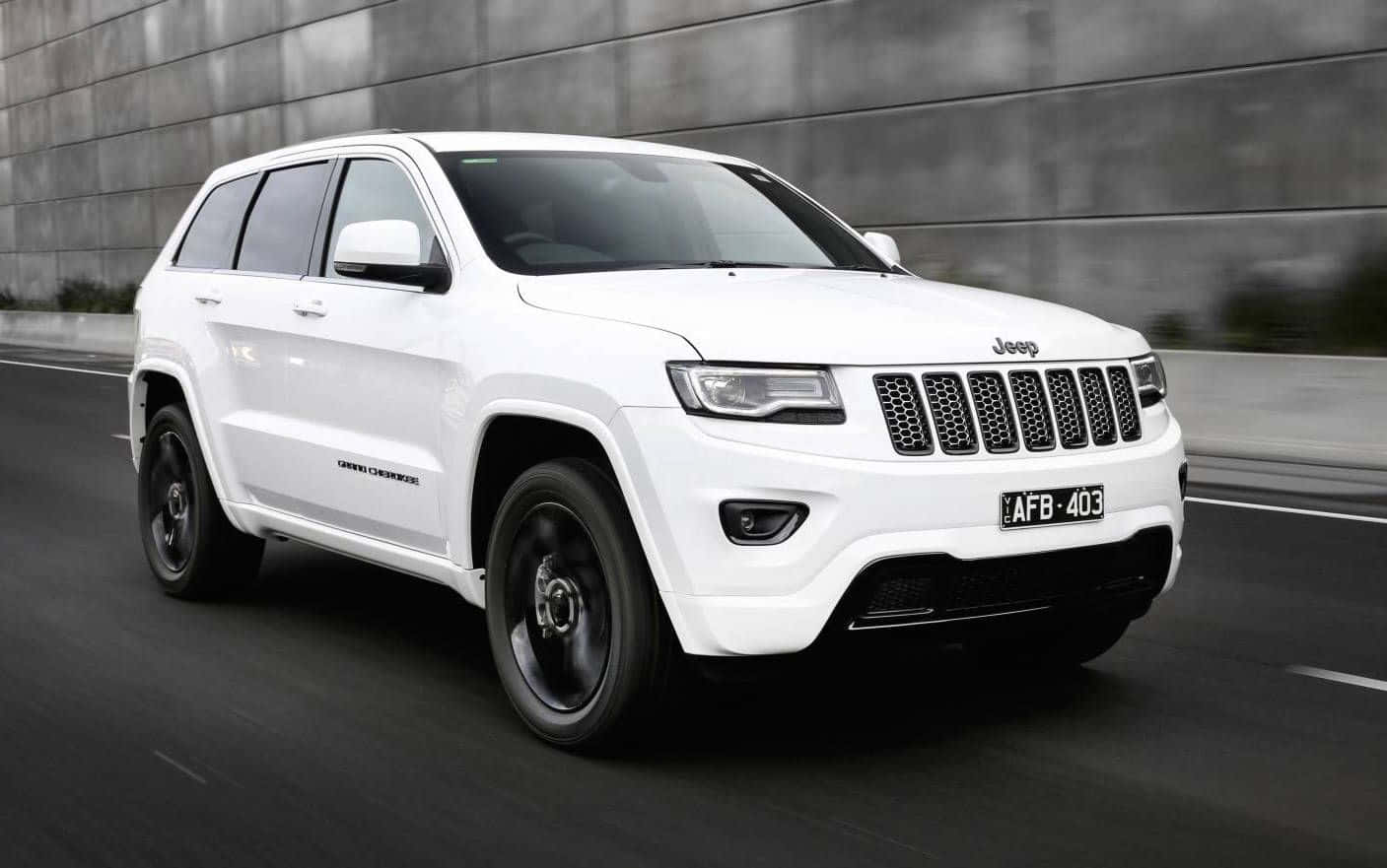 Family Car 桌布 壁紙 — 一架時尚的白色Jeep Grand Cherokee在現代城市道路上奔馳，帶有動態模糊效果，背景是灰色混凝土牆。