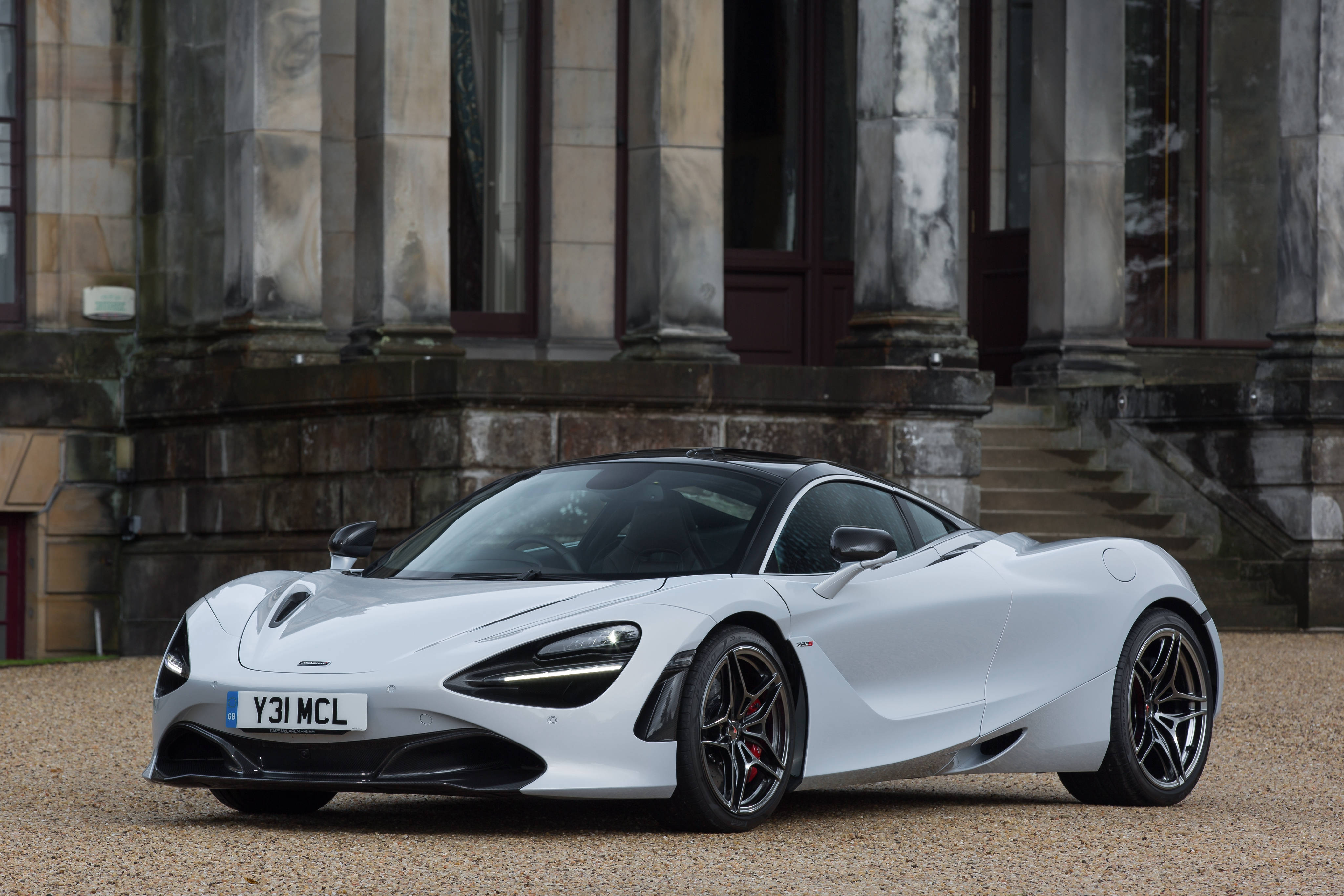mclaren 720s 4K 桌布 壁紙 — 一架時尚的白色McLaren 720S跑車停泊在碎石上，前方是一座有柱子的宏偉石建築。
