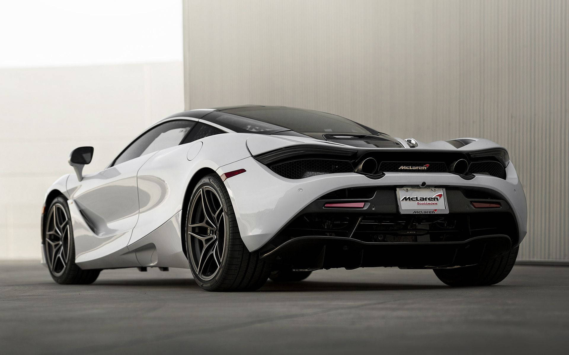 麥拉倫 桌布 壁紙 — 一架時尚的白色McLaren跑車帶黑色點綴，停放在室內，背景是簡約的混凝土牆。