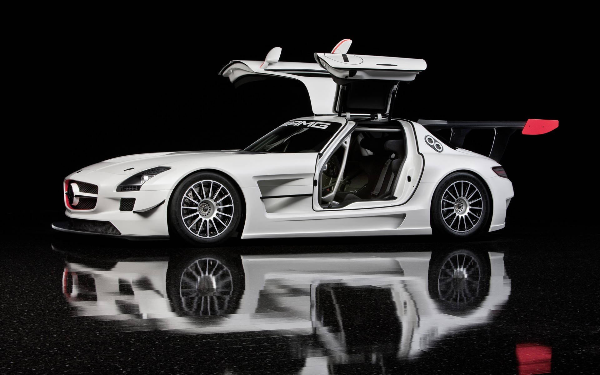 高畫質 賓士 桌布 壁紙 — 一架時尚的白色Mercedes-AMG SLS GT1超級跑車，鷗翼車門打開，在深色背景下映照在光亮的黑色工作室地板上。